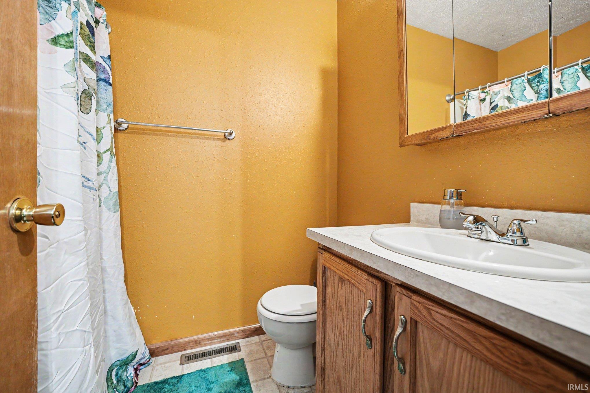 Bathroom with a wood-finish vanity, integrated sink, and laminate countertop
