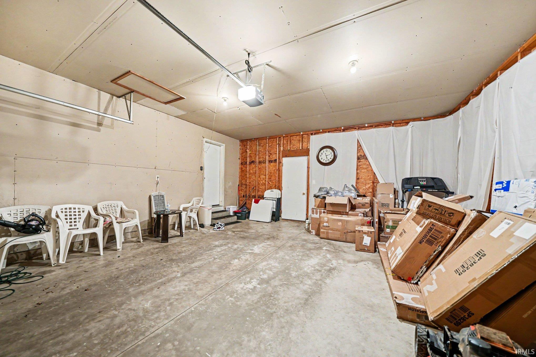 Spacious garage featuring a concrete floor, exposed wood framing, and multiple light fixtures