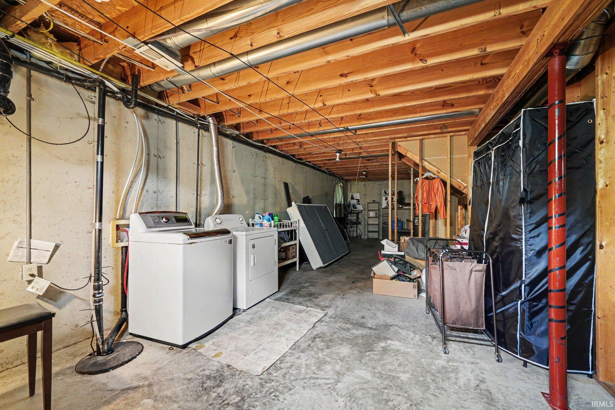 Unfinished basement featuring exposed wood joists and concrete walls