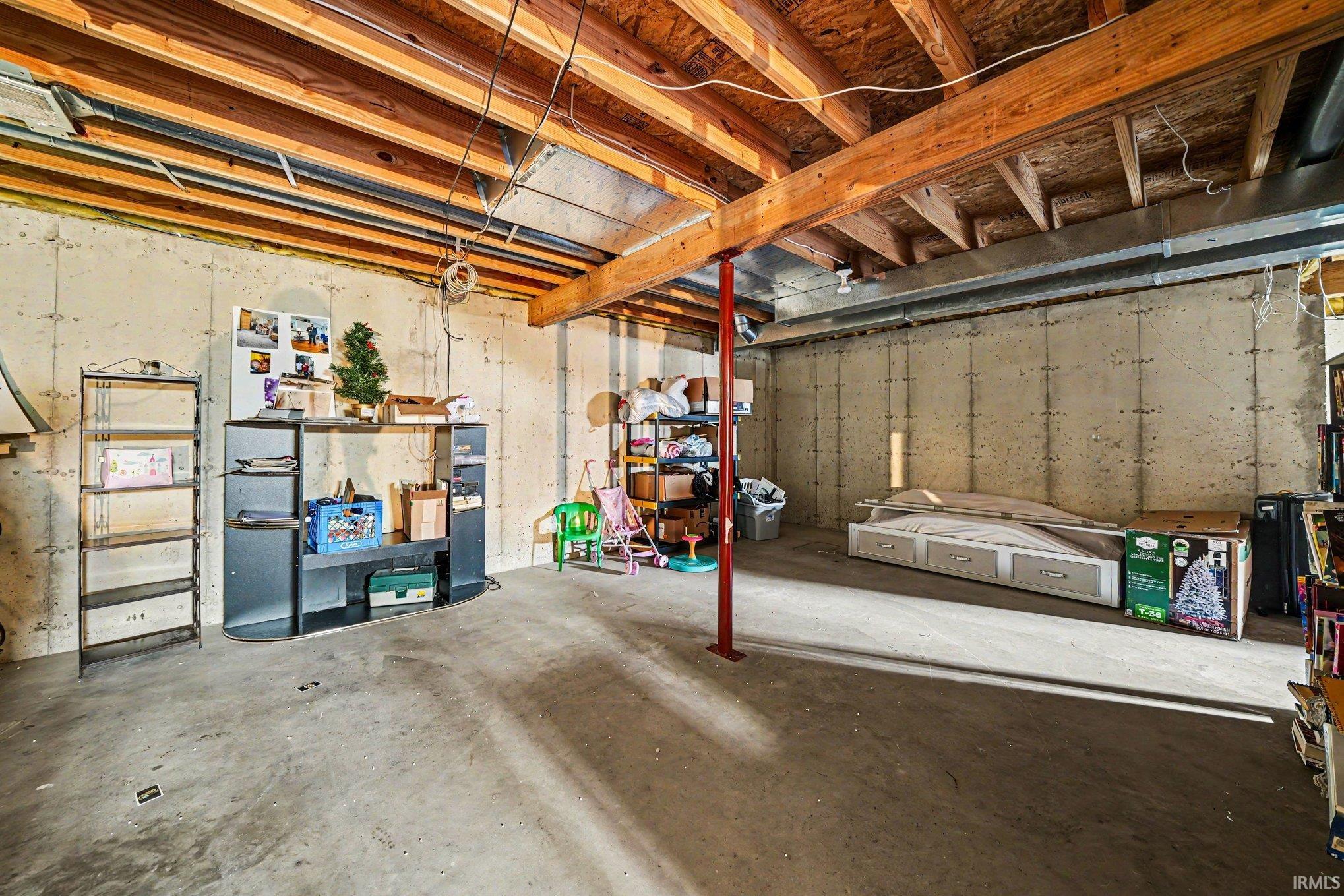 Unfinished basement featuring exposed wood ceiling joists, concrete walls, concrete flooring, and an exposed support beam