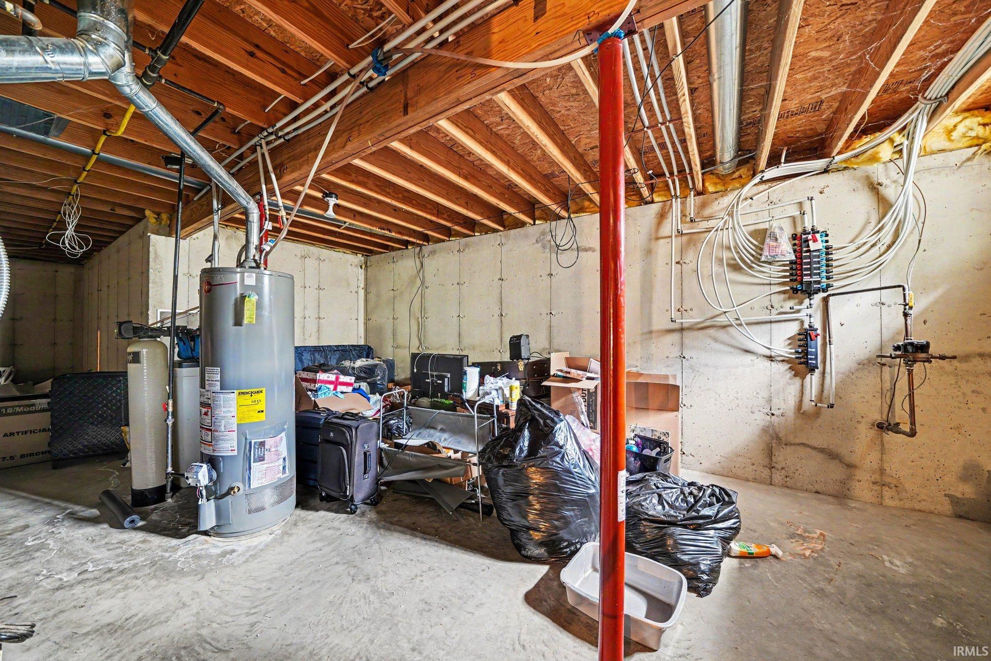 Unfinished basement offering exposed ceiling joists, concrete foundation walls, and visible plumbing and electrical infrastructure