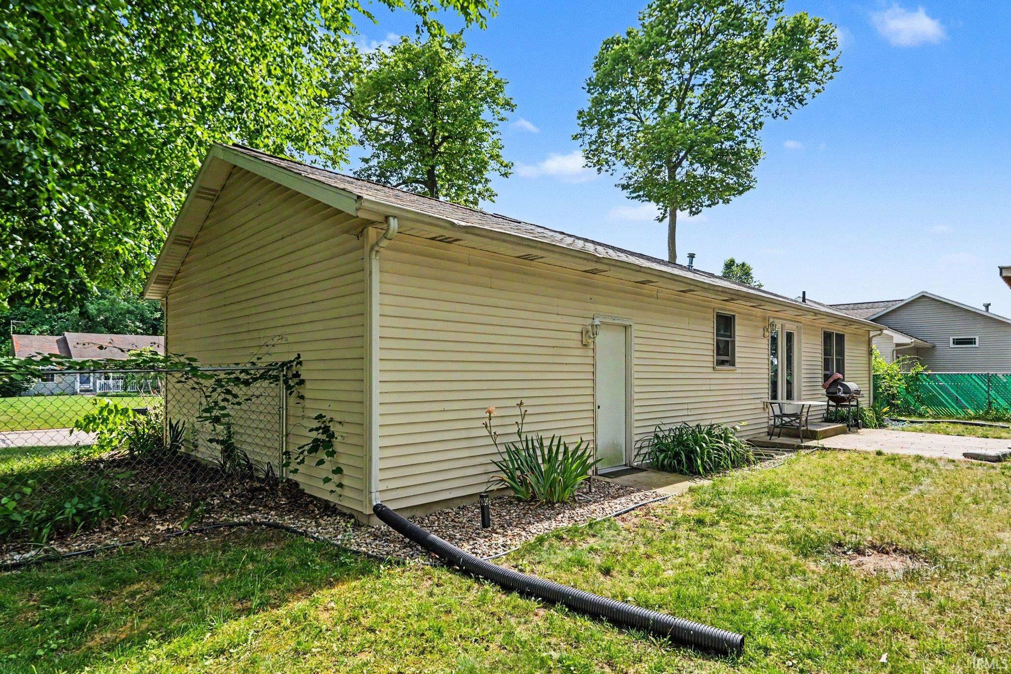 Exterior of property featuring beige siding, a side entry door, and a concrete patio