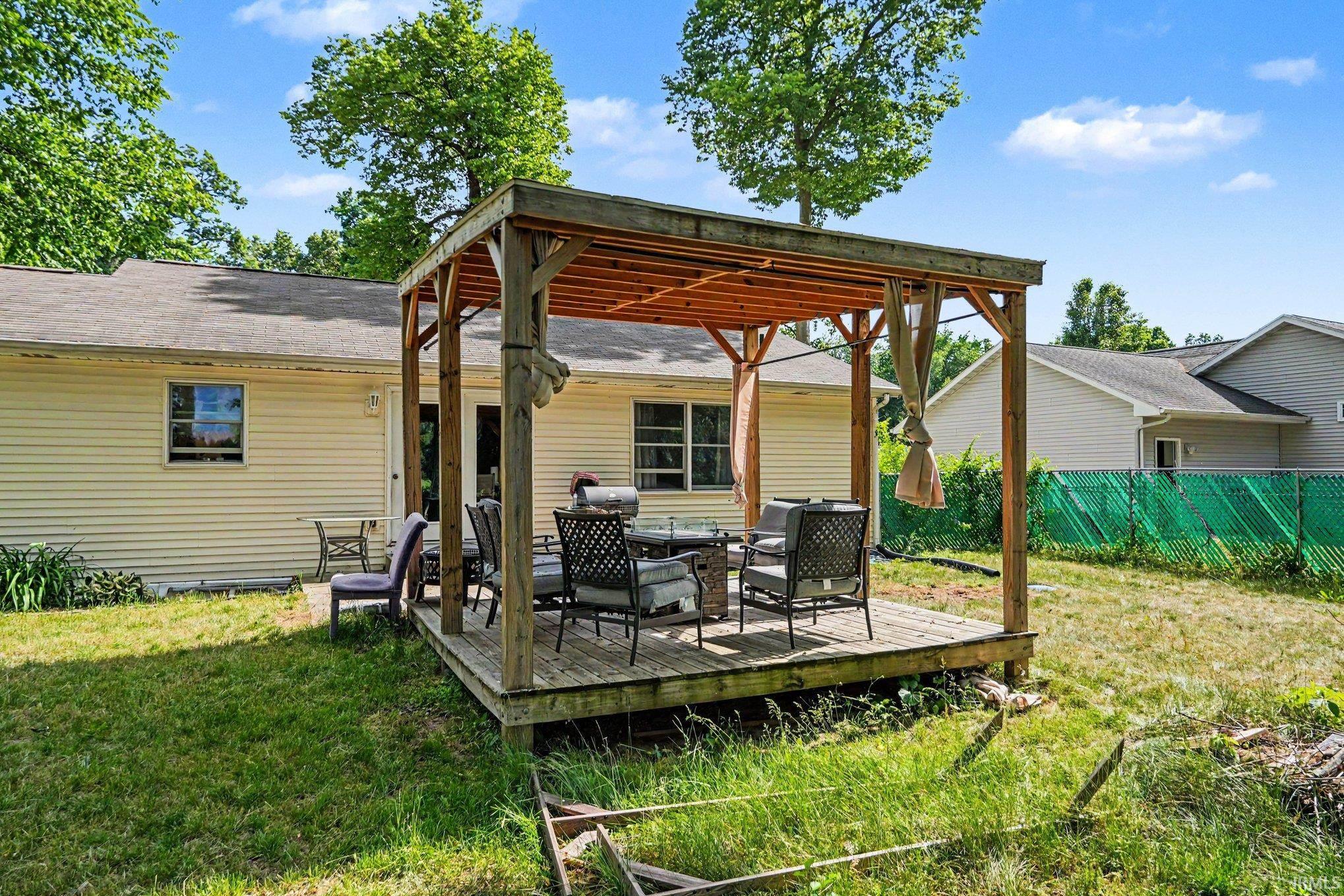 Expansive outdoor deck featuring a wooden pergola with sunshades, offering direct access to the home's rear entrance