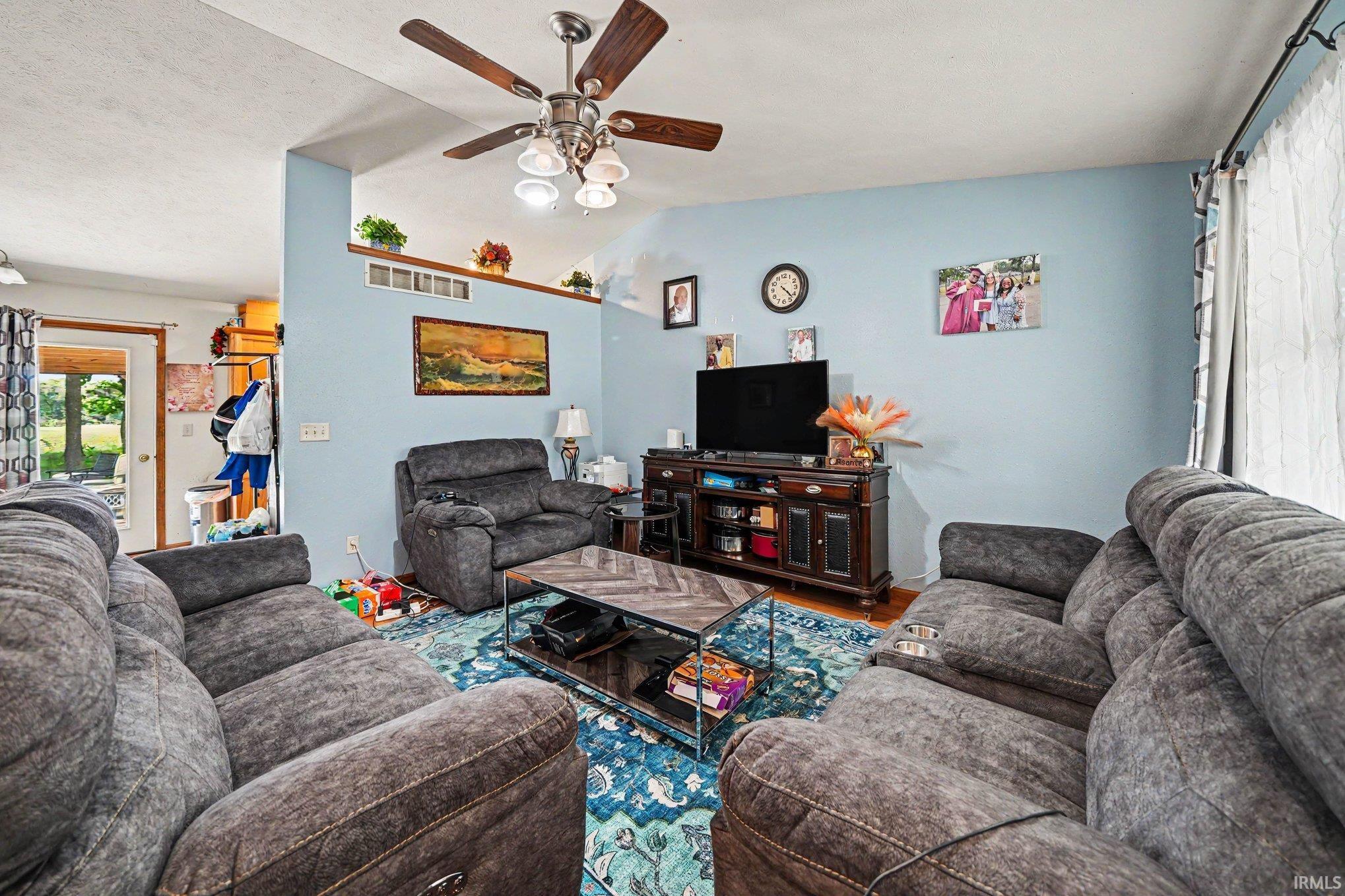 Living area featuring a ceiling fan with light fixture, light blue walls, and a recessed display shelf