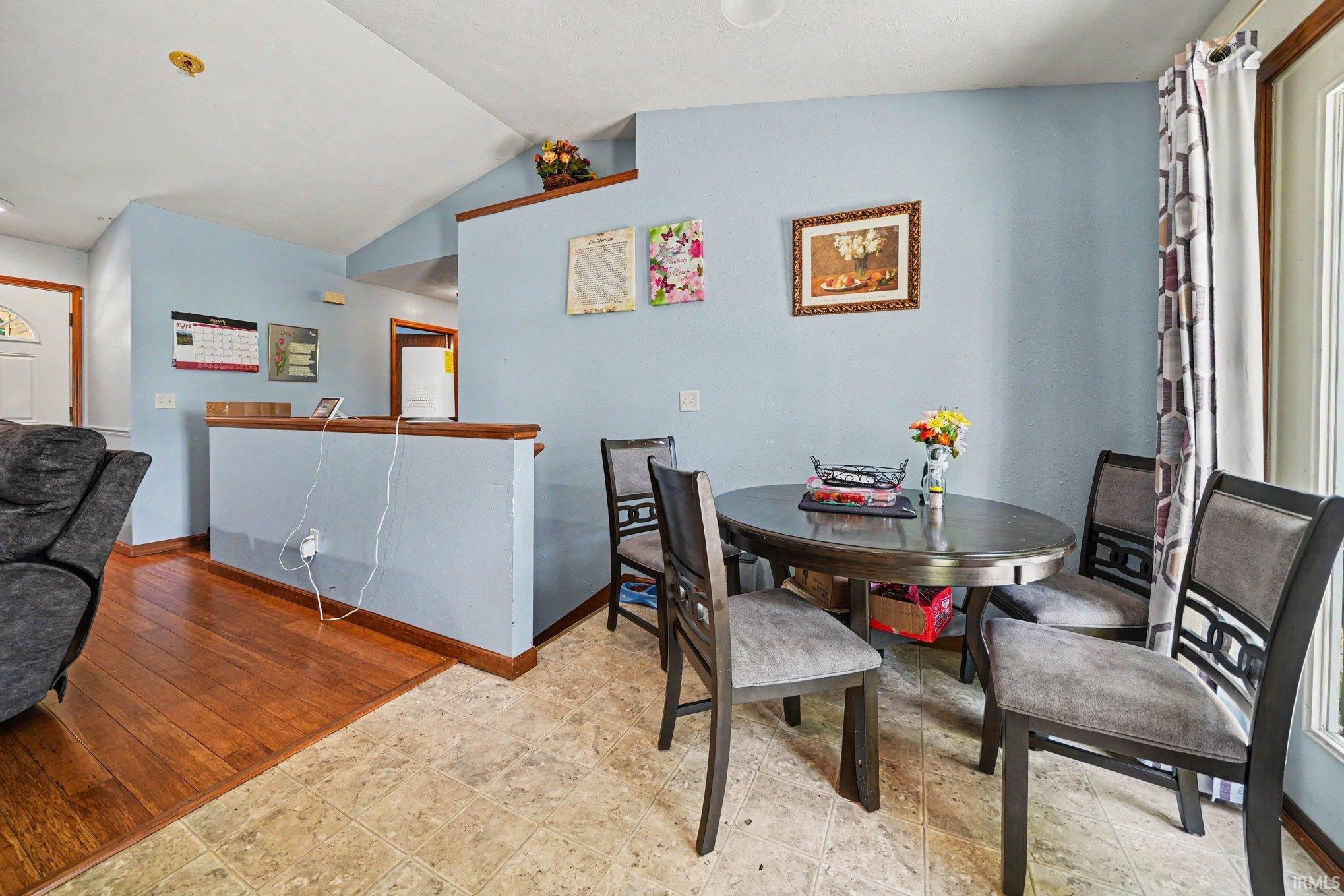 Dining area featuring tiled flooring transitioning to wood-finish flooring