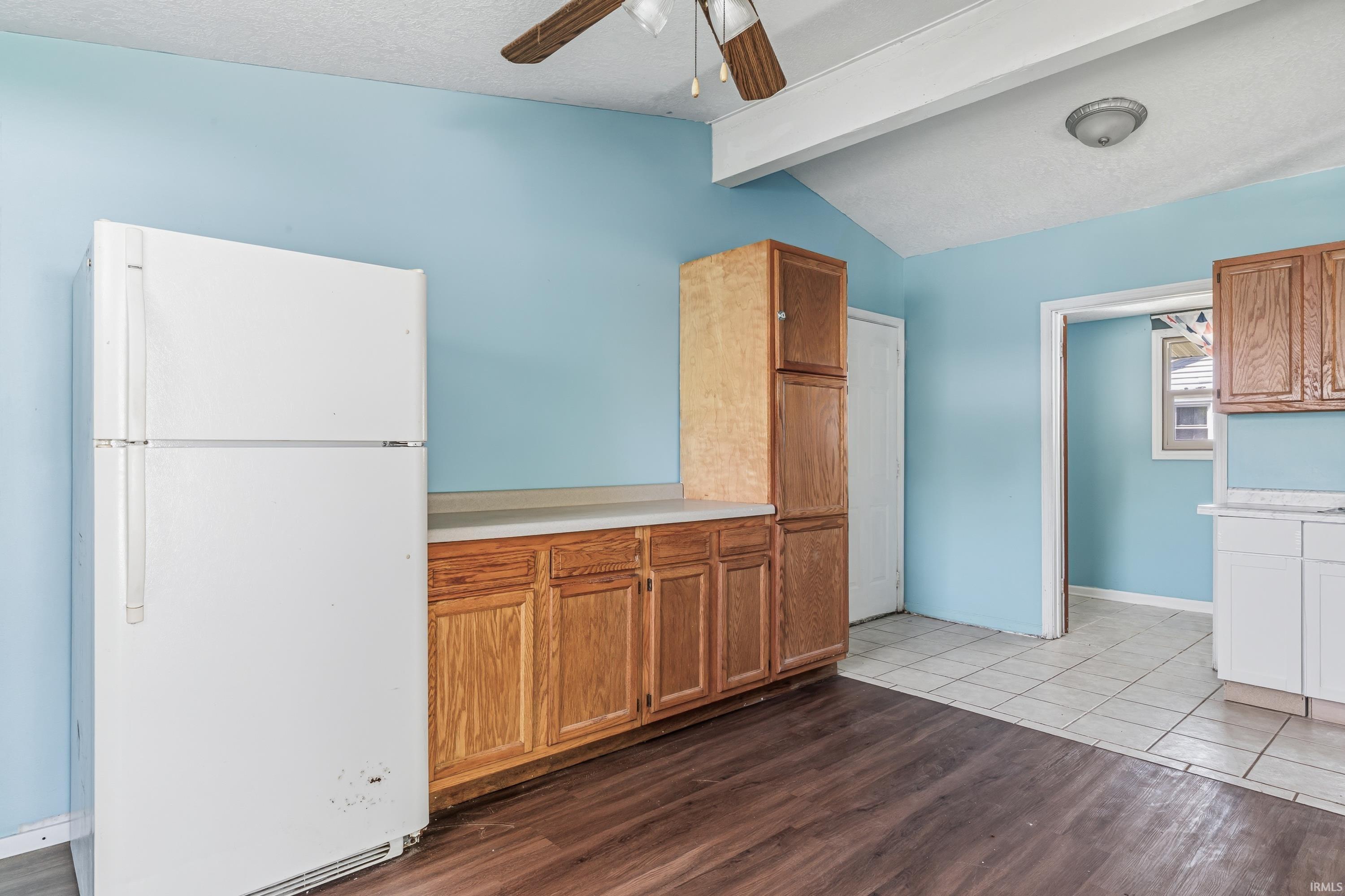 Kitchen area featuring wood-finish flooring, light blue walls, and a white refrigerator