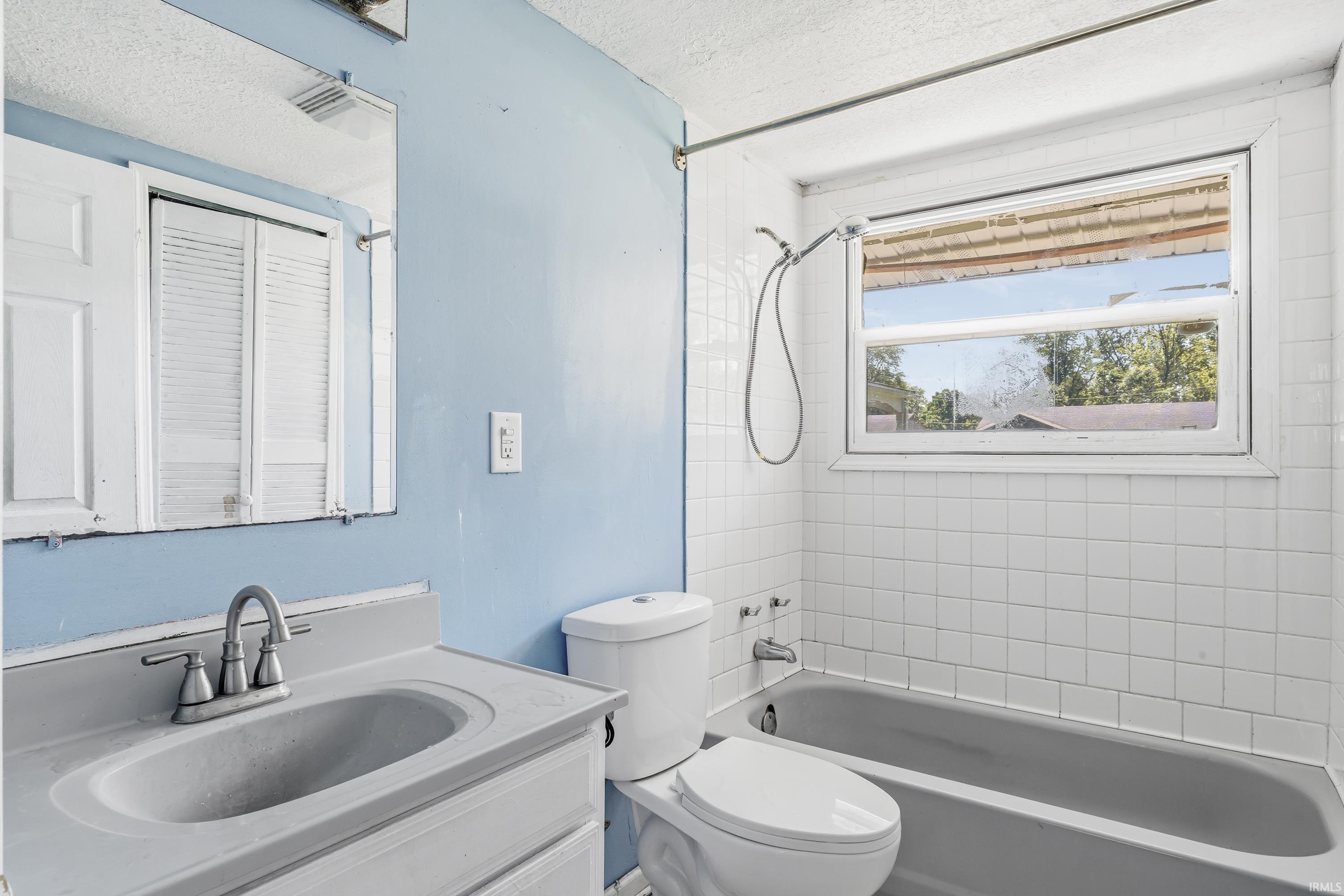 Bathroom featuring a white vanity with integrated sink, chrome faucet, and mirrored medicine cabinet