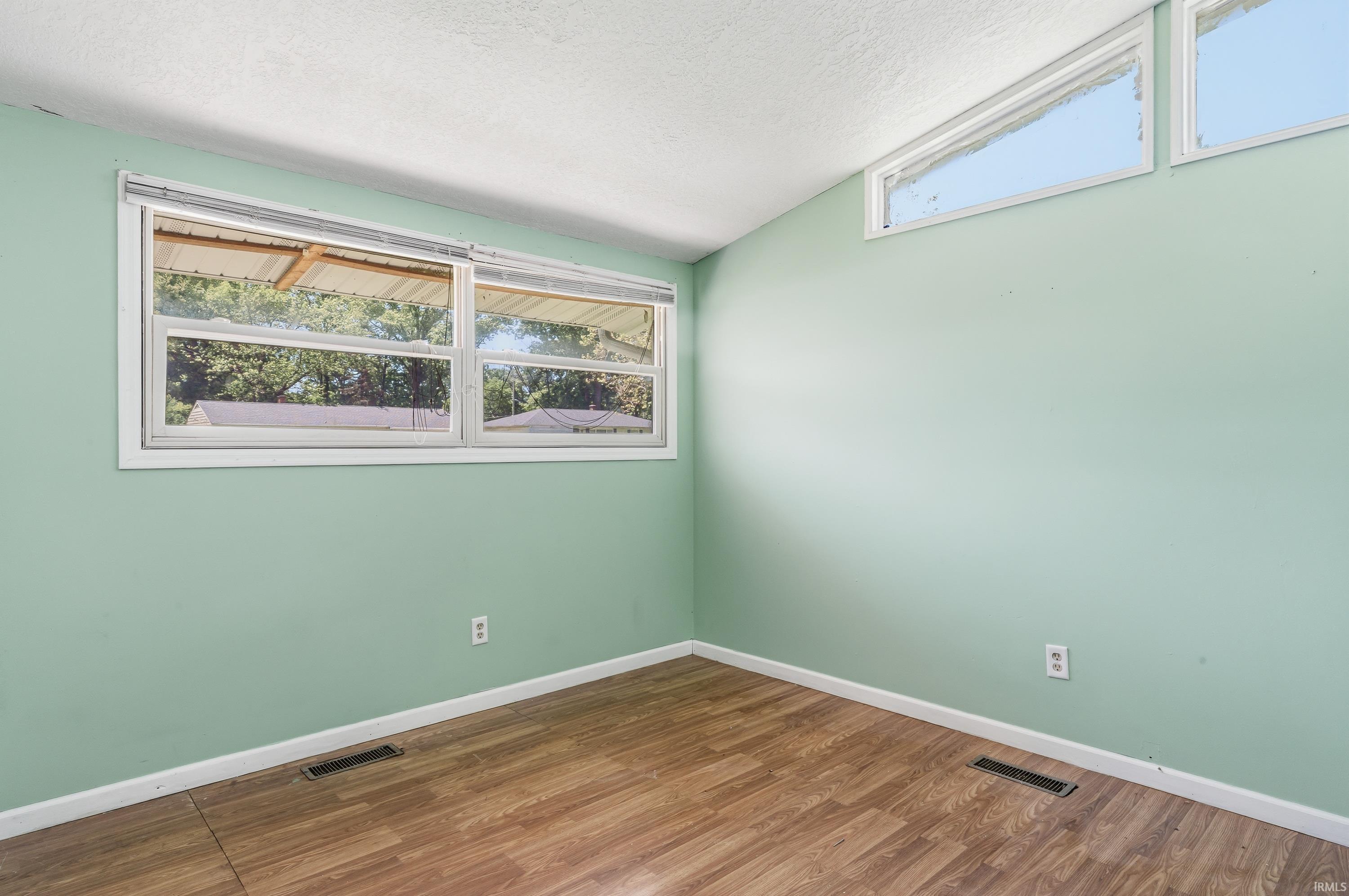Room featuring wood-finish flooring, light green walls, and white trim