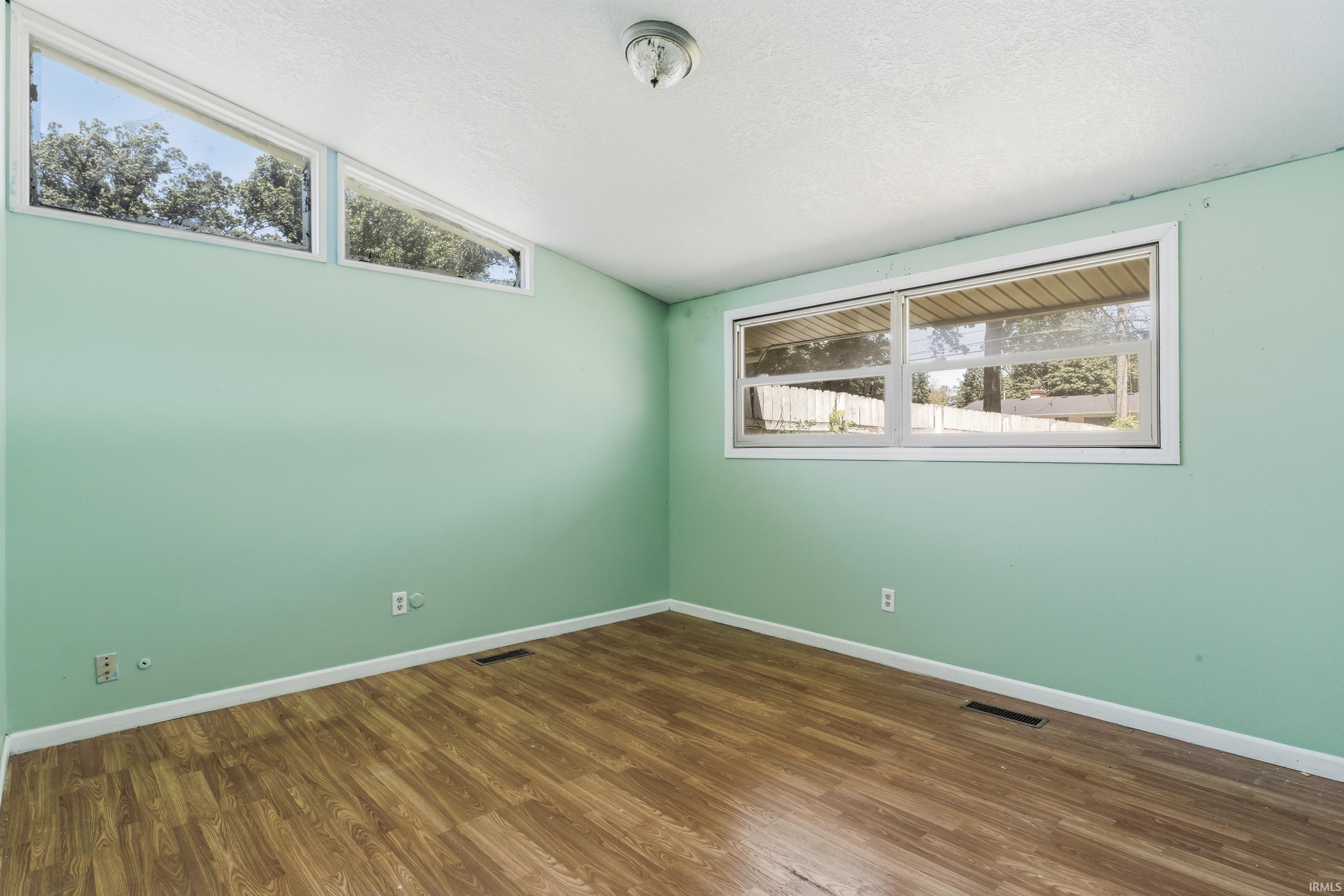 Room featuring wood-finish flooring, light green painted walls, white trim, and a textured white ceiling