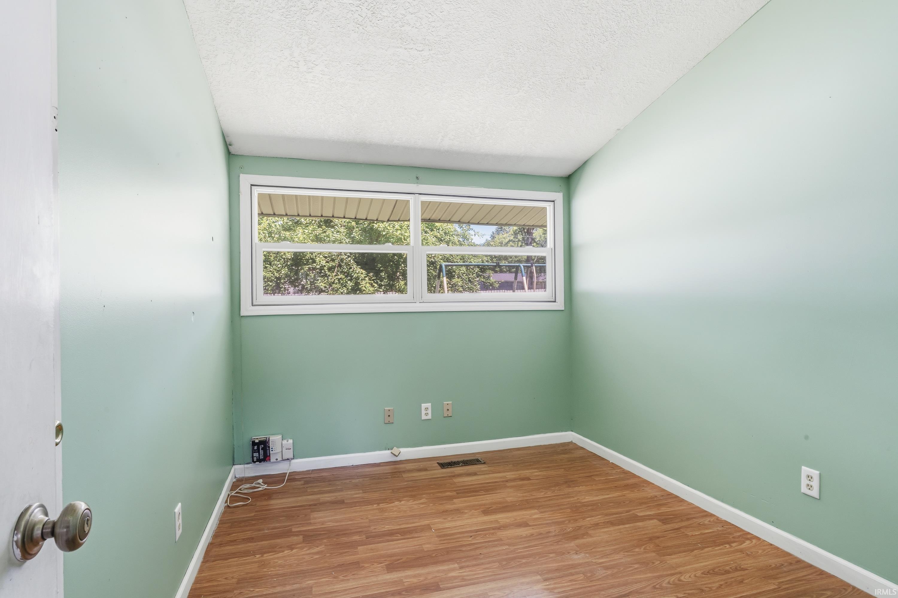 Room featuring wood-finish flooring, light green painted walls, and white trim