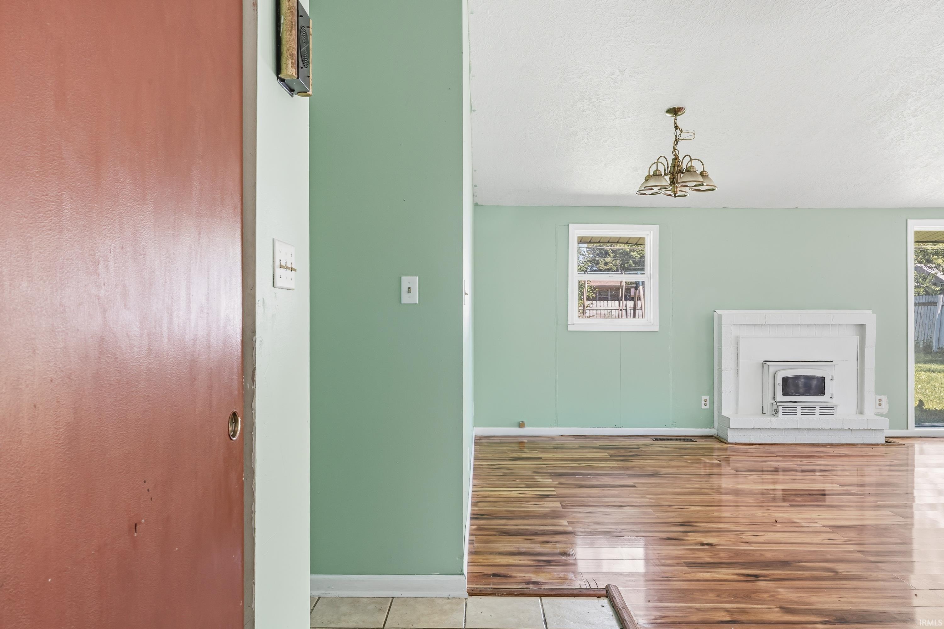 Spacious room featuring wood-finish flooring, a white mantel, and a built-in fireplace insert
