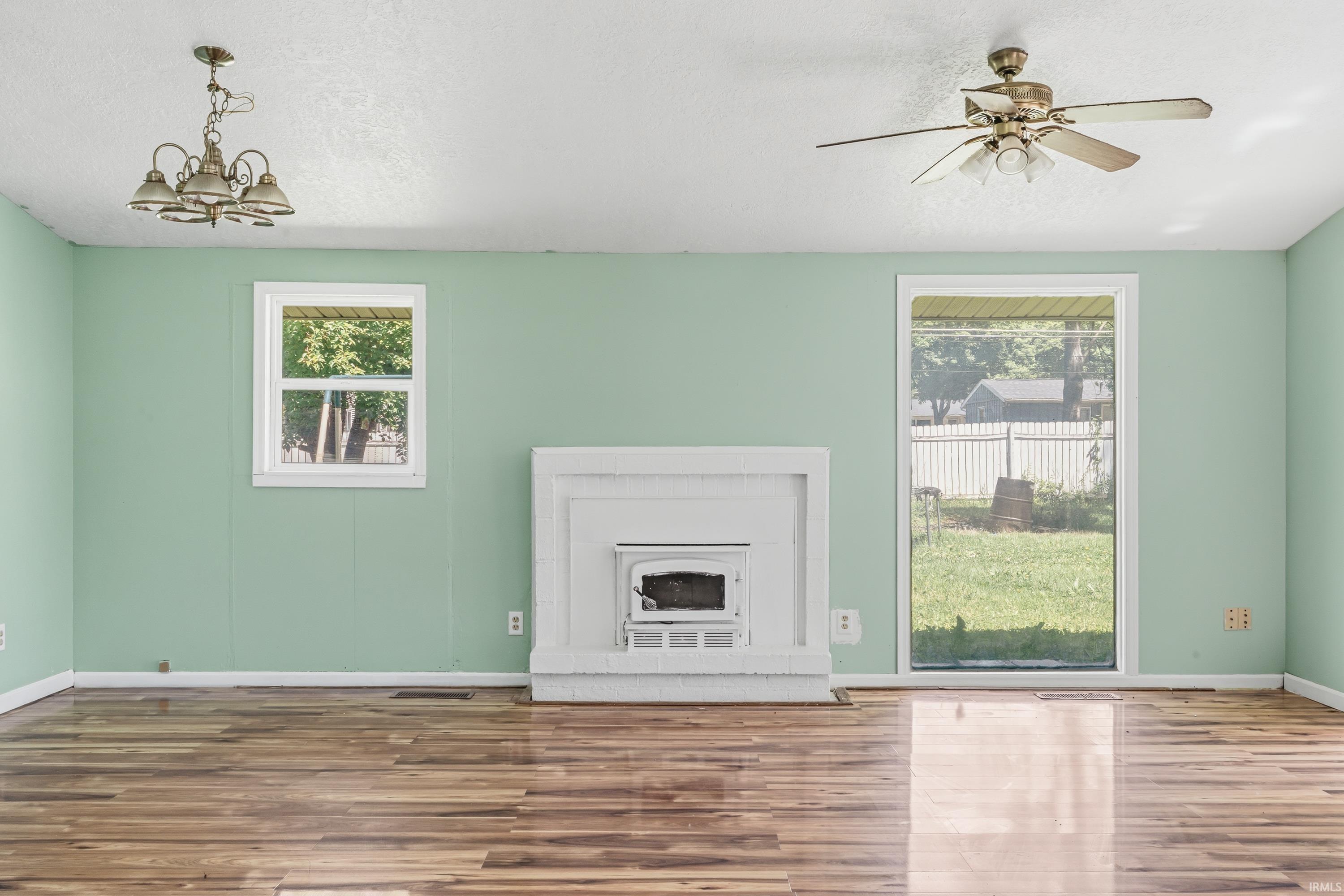 Living space featuring wood-finish flooring, a white fireplace surround with an insert, and light green walls