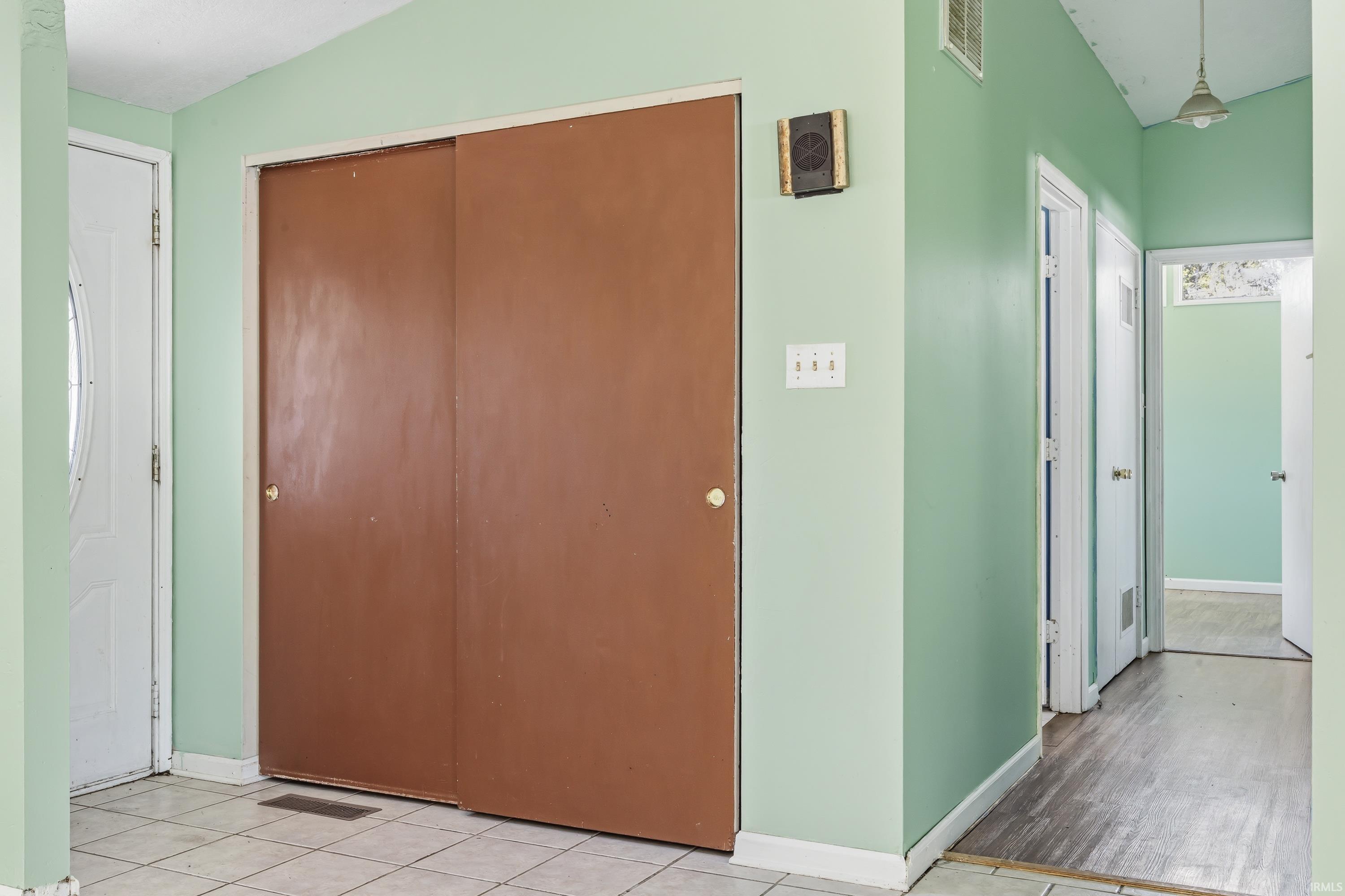 Entryway featuring a tiled floor, double sliding closet doors, and light green wall paint