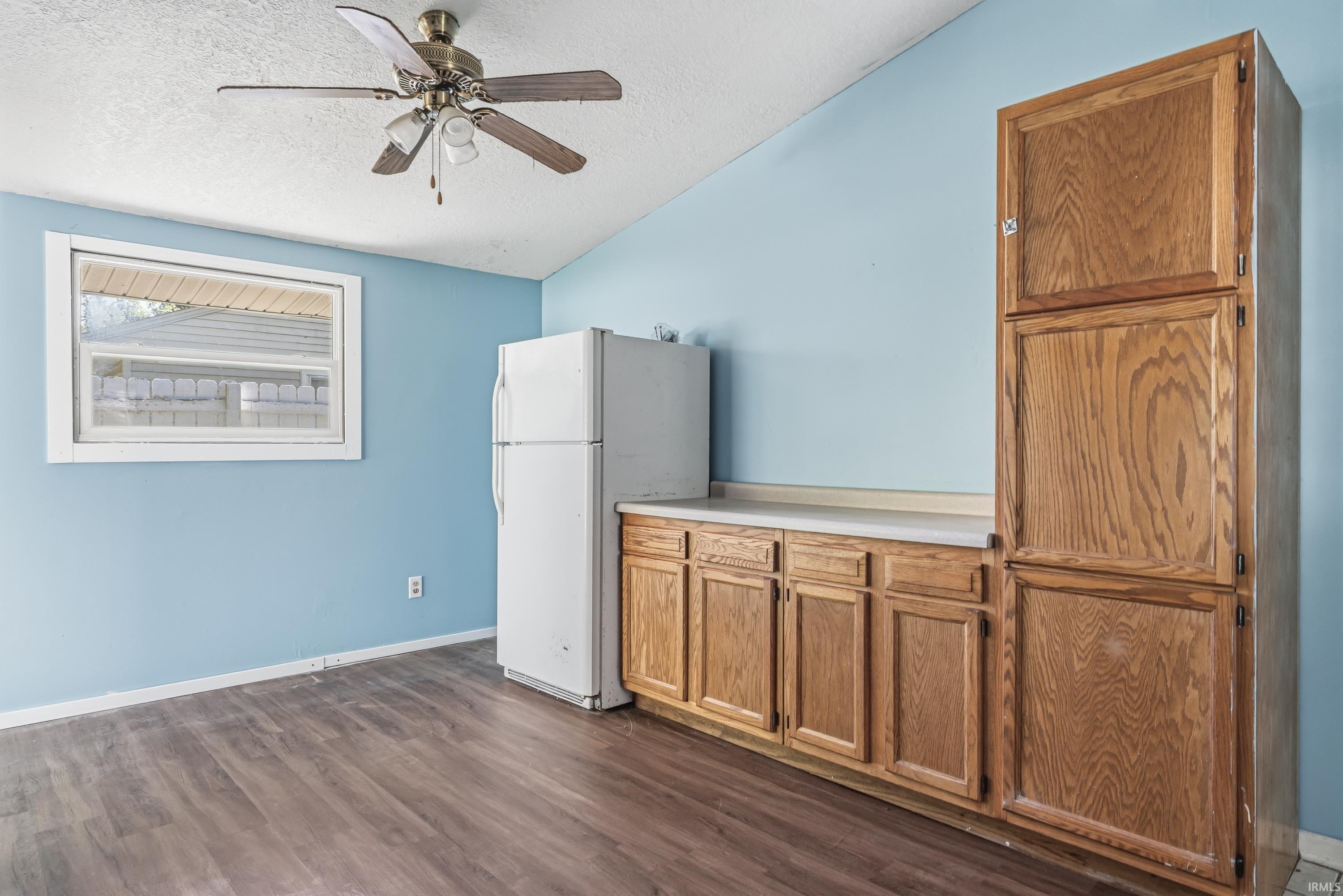 Kitchenette area featuring wood-finish flooring, white countertop, wood cabinetry, and a ceiling fan with integrated lighting