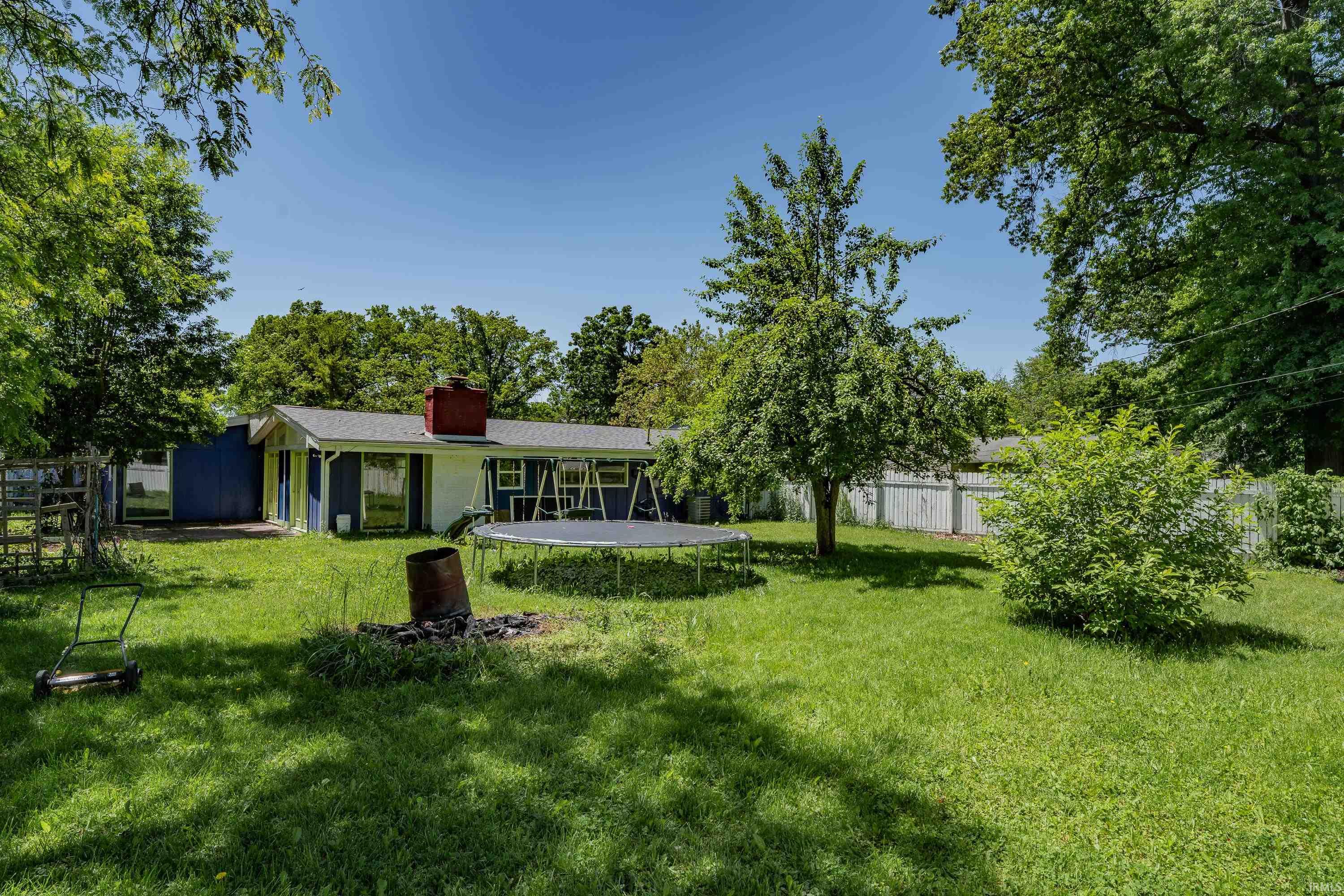 Spacious backyard featuring a lush lawn, mature trees, and a visible privacy fence