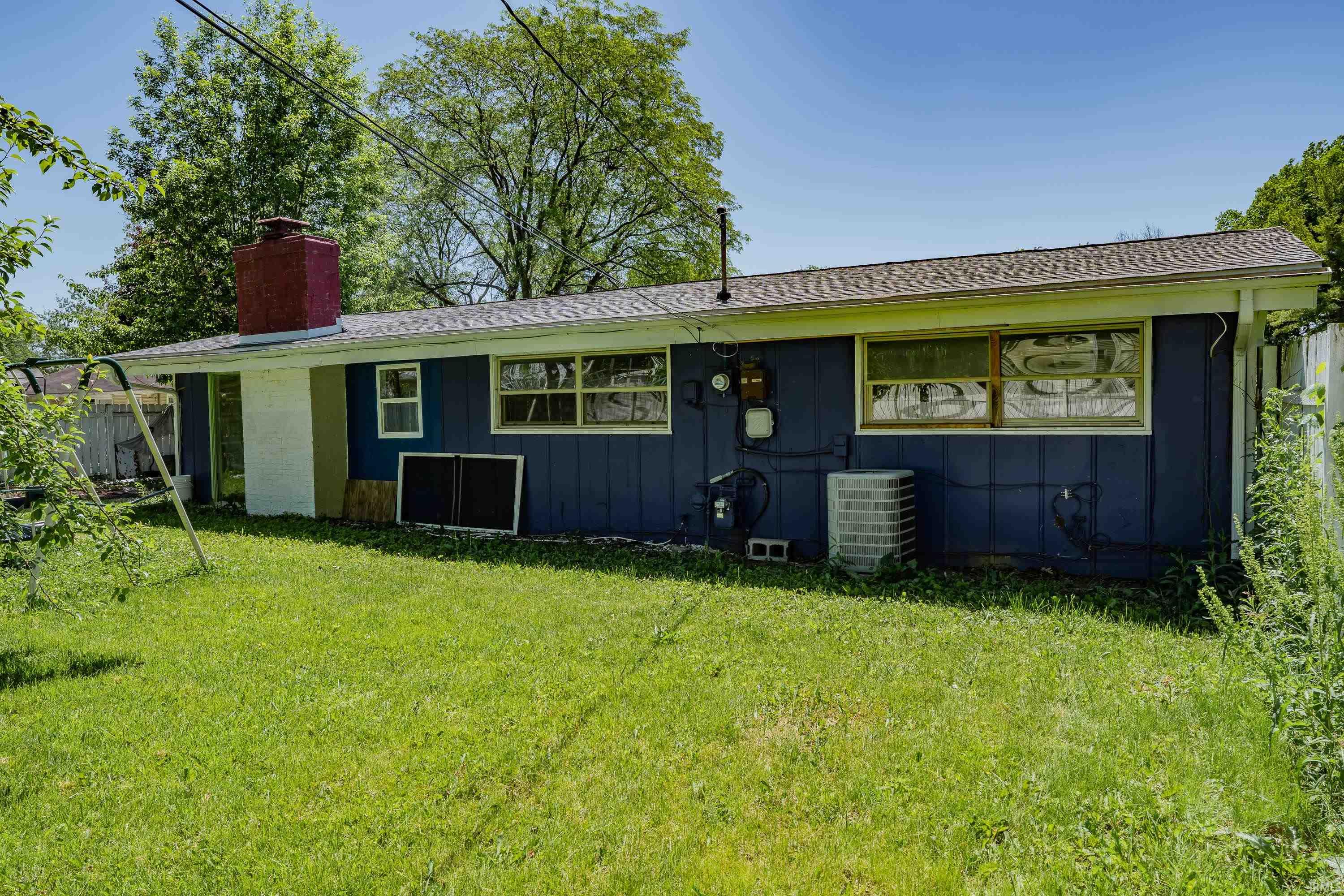 Rear exterior featuring blue siding and a red brick chimney