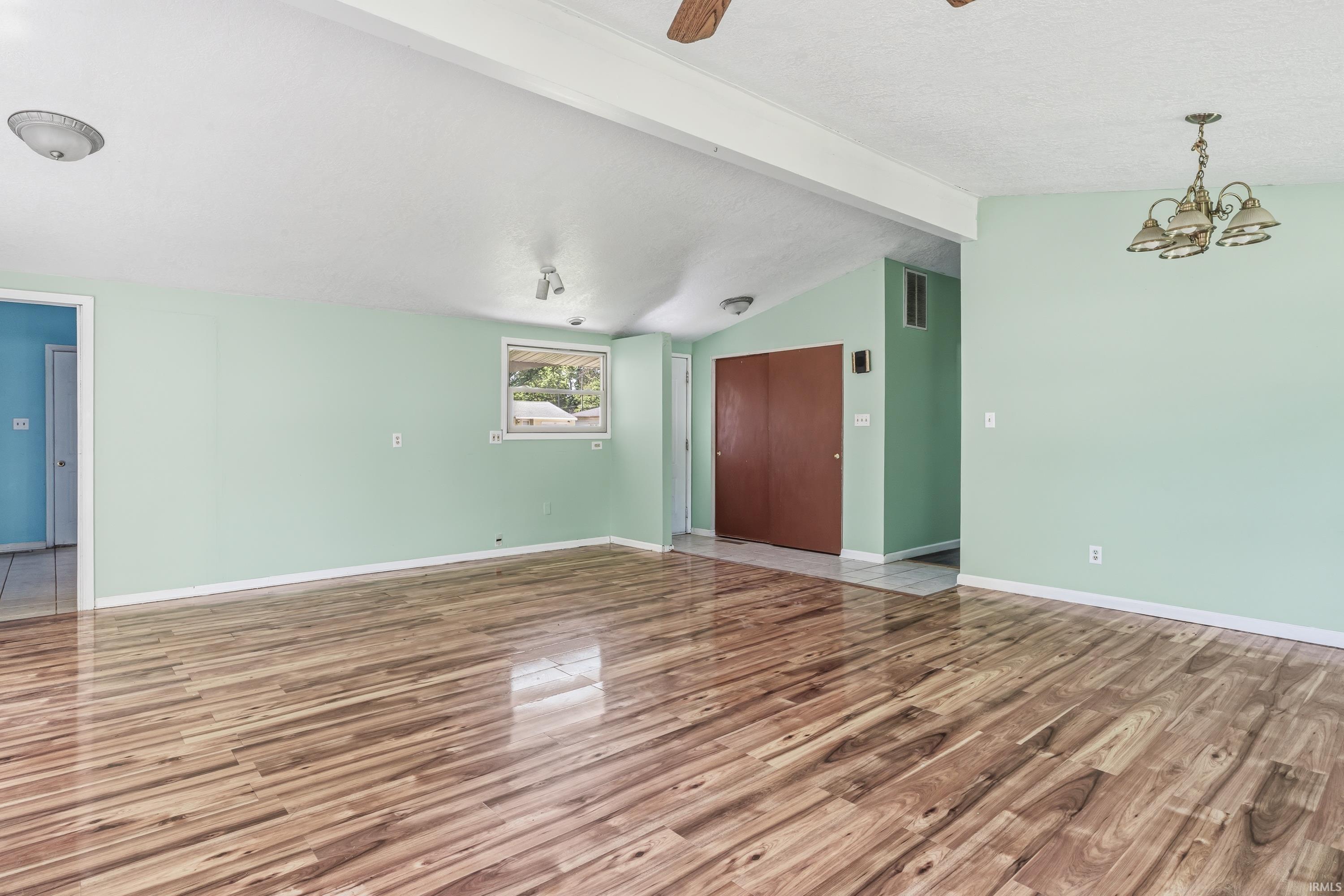 Spacious room featuring wood-finish flooring, a window providing natural light, and a sloped ceiling portion