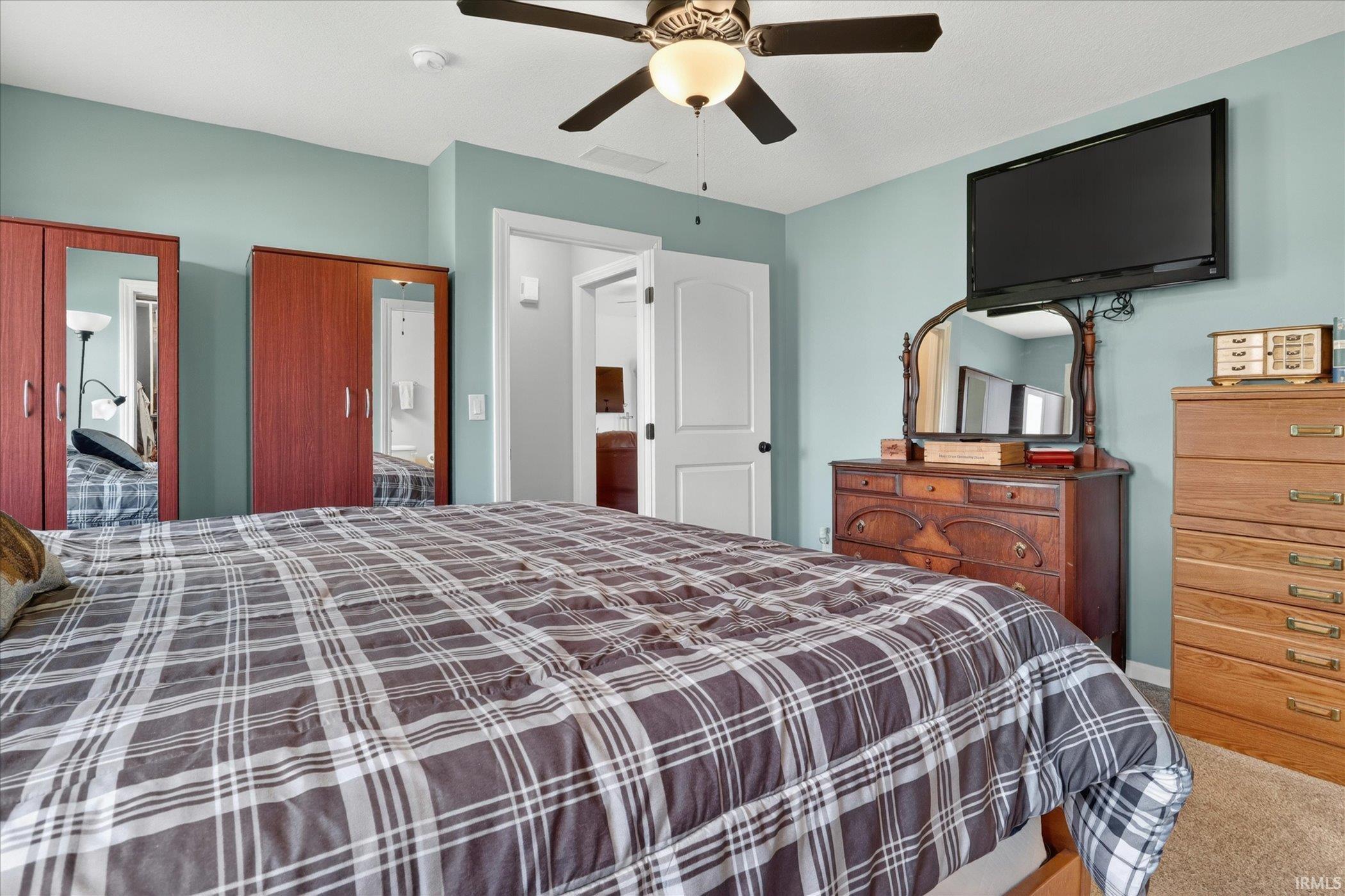 Carpeted room with a ceiling fan, light blue walls, and a white door opening into an adjoining space