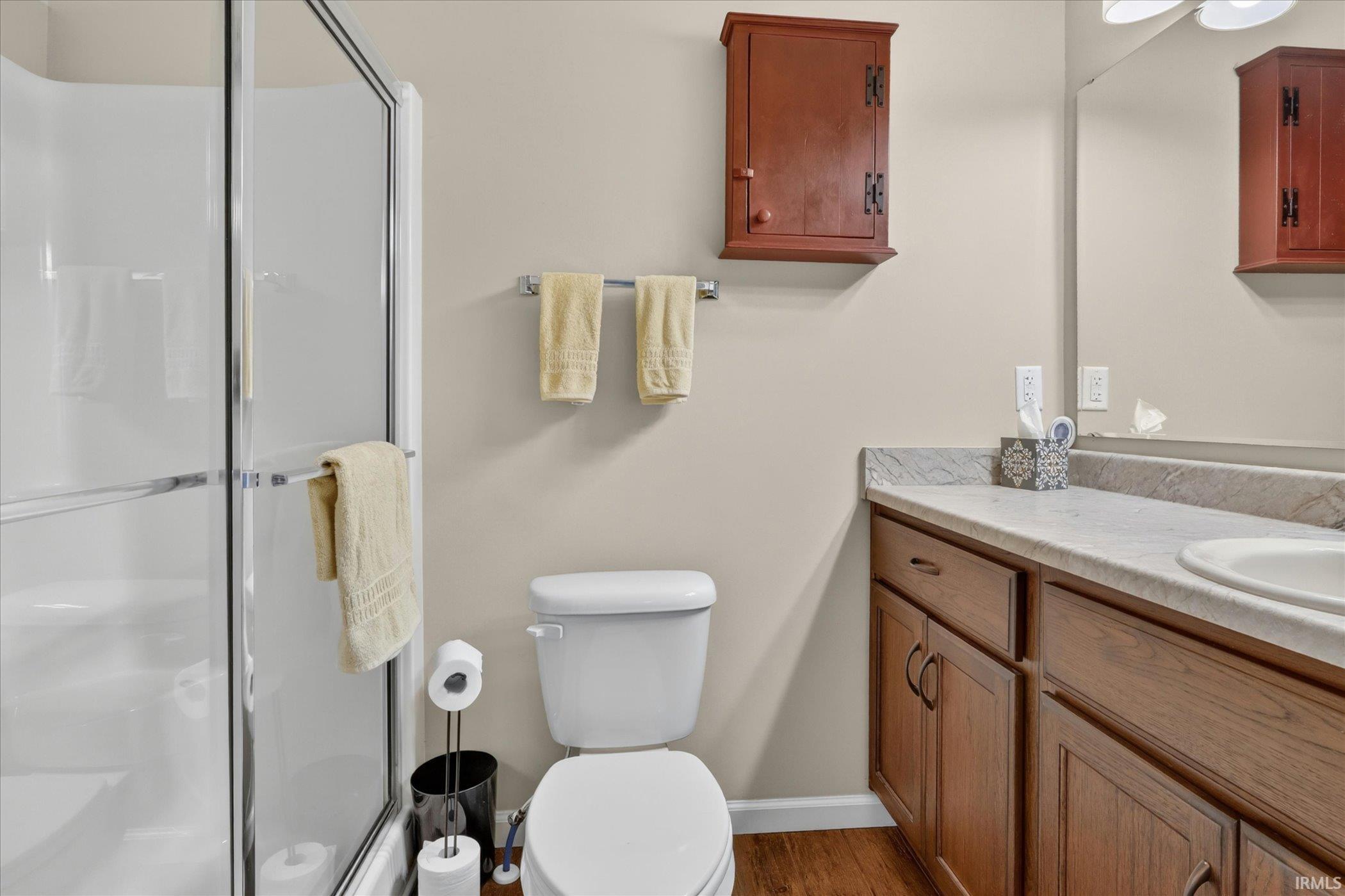 Bathroom featuring a glass-enclosed shower, a vanity with wood cabinetry, a built-in sink, and a countertop