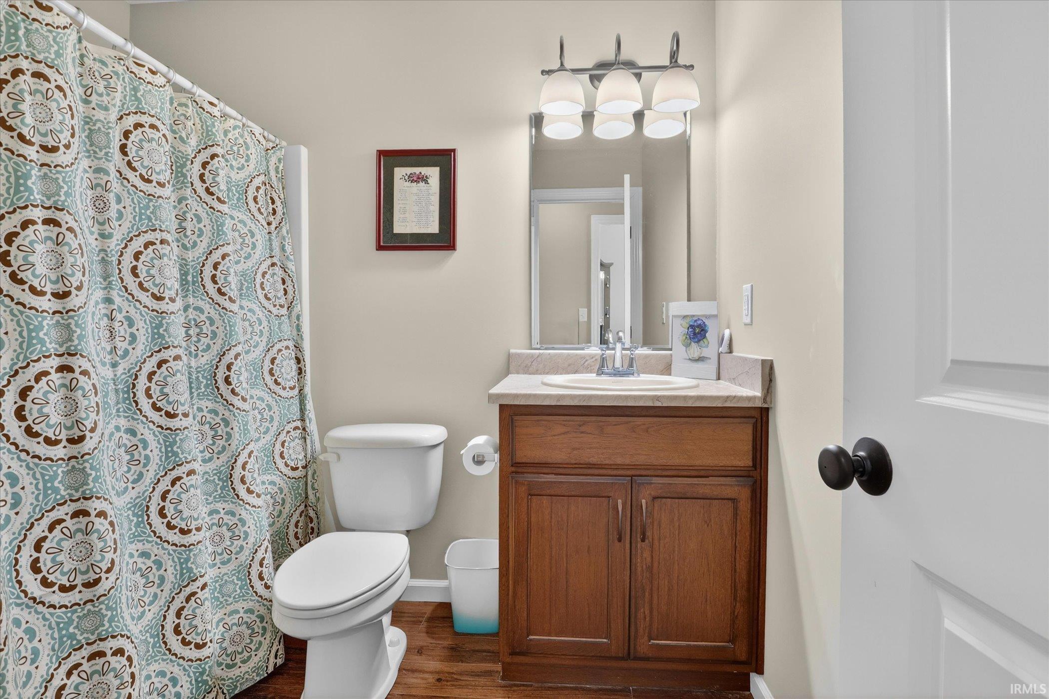Bathroom featuring a wood-finish vanity with a light-toned countertop and an integrated sink