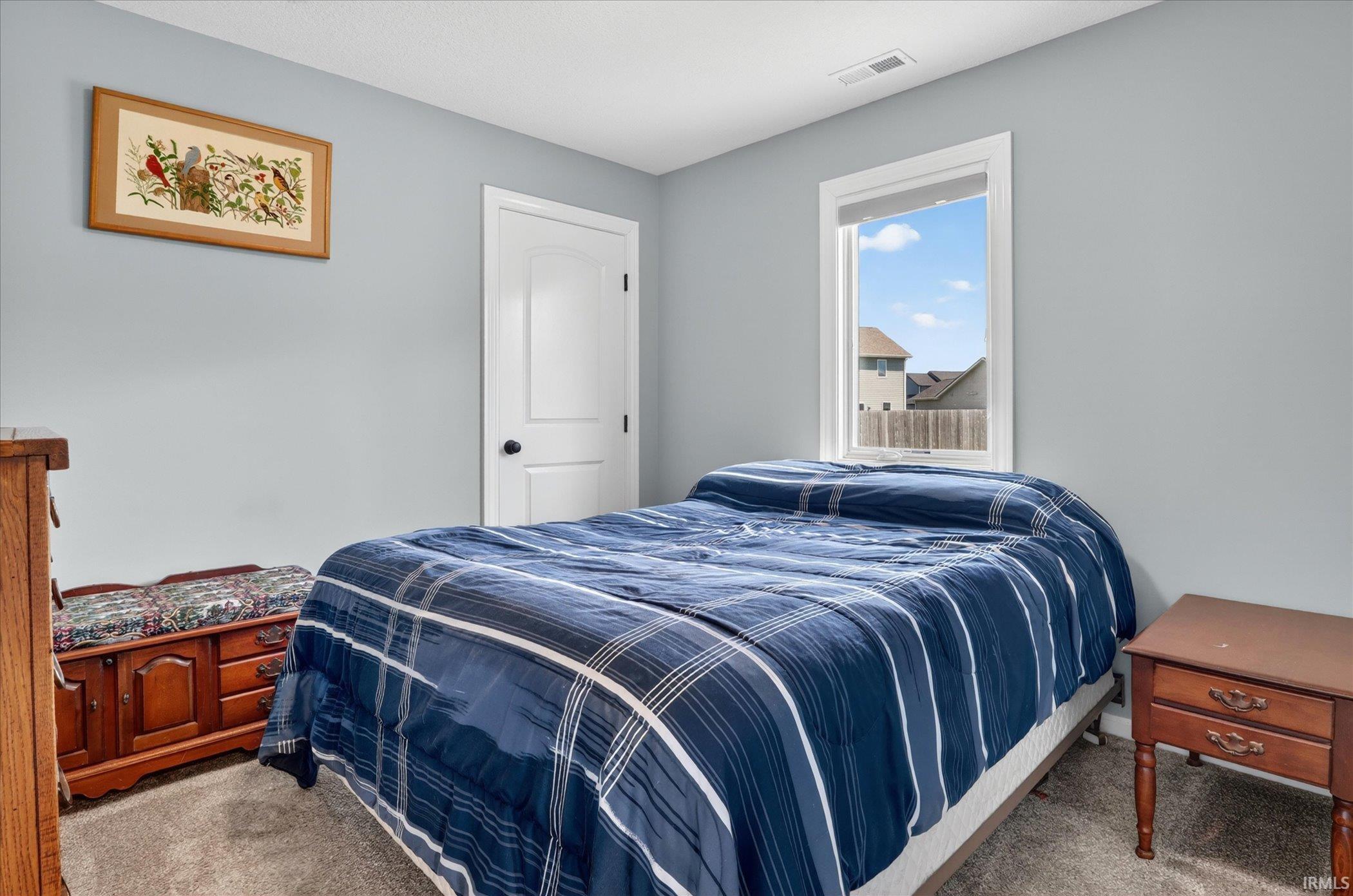 Bedroom featuring neutral gray wall paint, a single window with white trim, and light gray carpet flooring