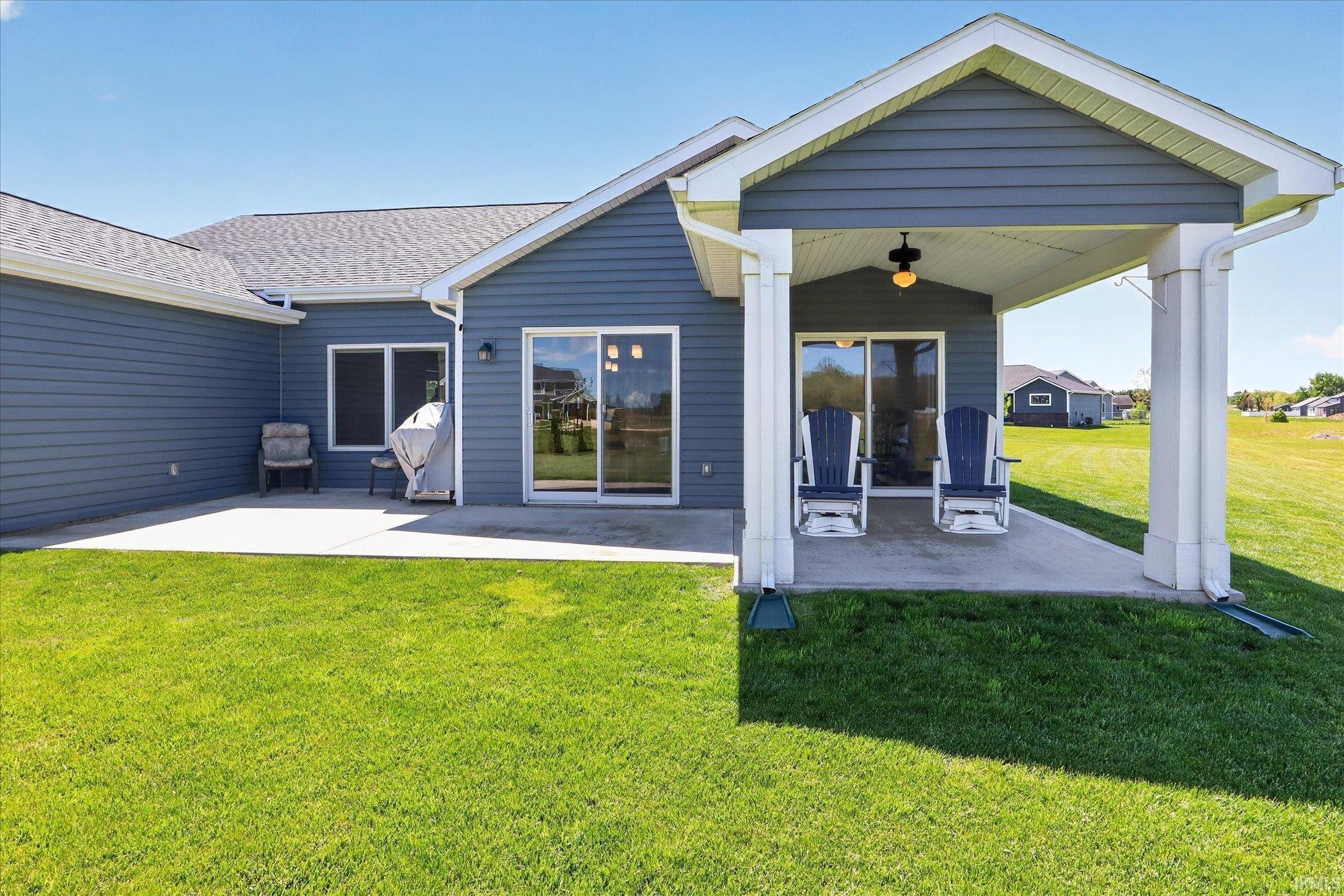 Spacious backyard featuring a covered patio with recessed lighting, an expansive concrete patio, and a large grassy area