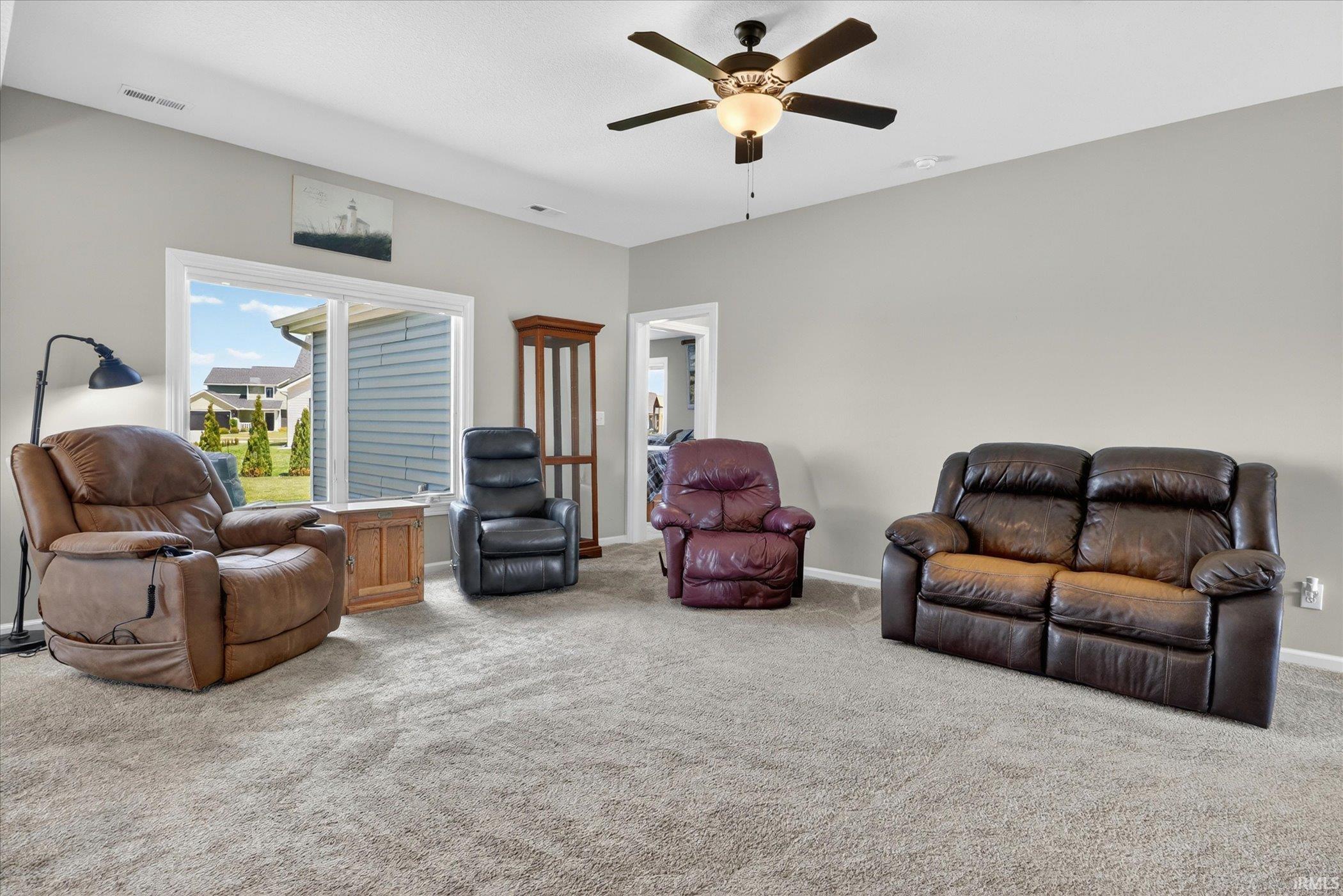 Carpeted living space featuring light gray wall paint and a ceiling fan with integrated lighting