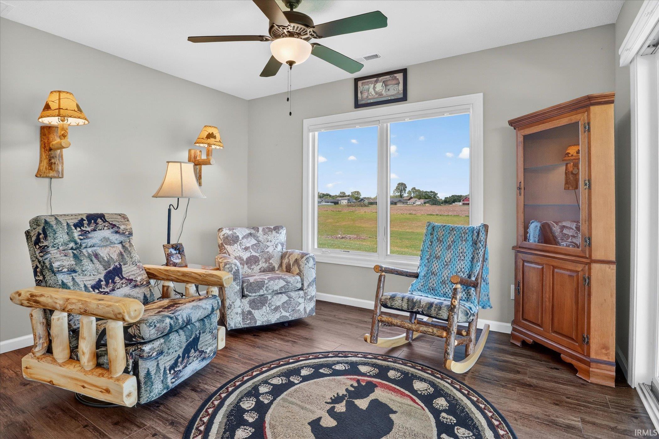 Bright interior space featuring wood-finish flooring, a ceiling fan with integrated lighting, and multiple windows offering expansive exterior scenery