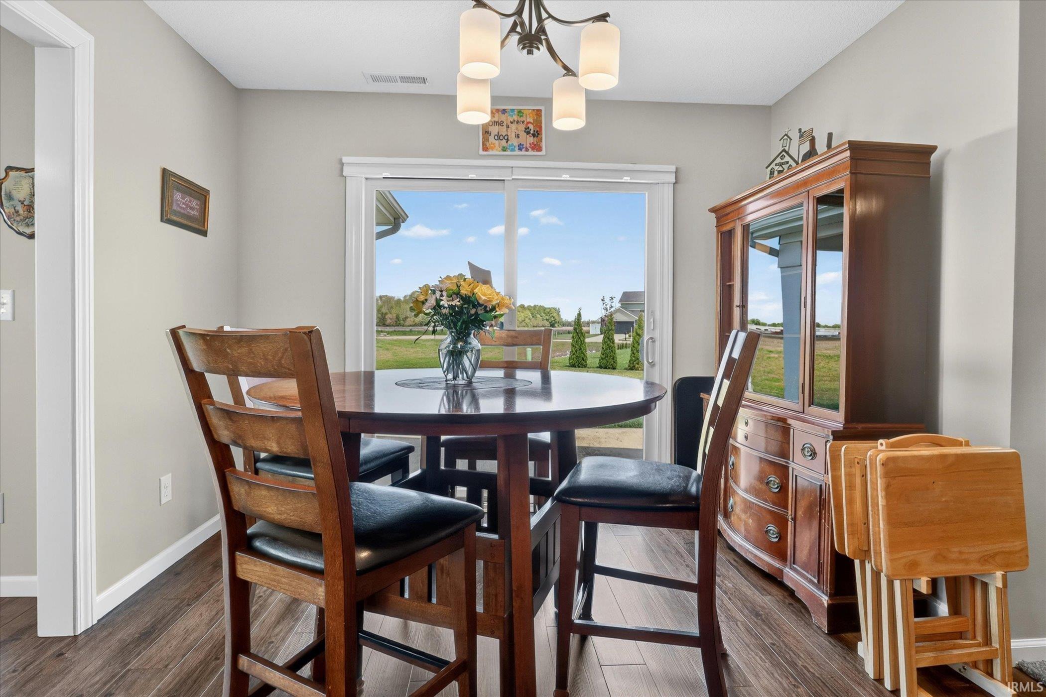 Dining area featuring wood-finish flooring, light gray walls, and a glass sliding door