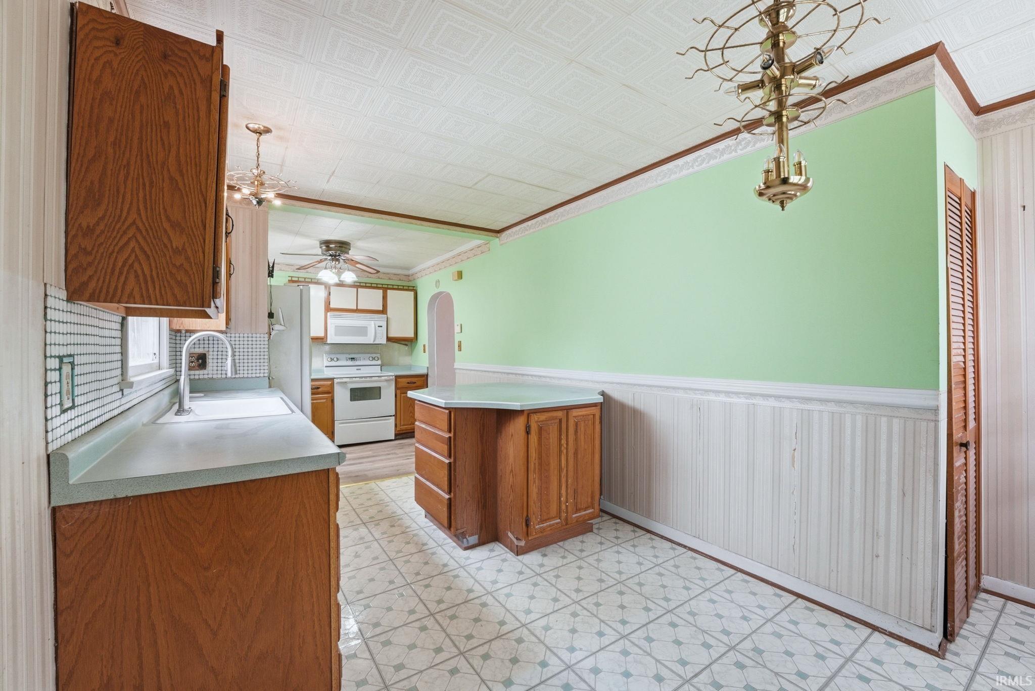 Kitchen area featuring wood cabinetry, white appliances, and a built-in island with countertop