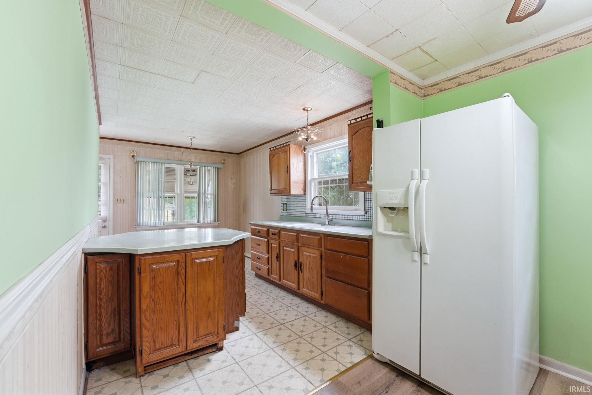 Kitchen featuring wood cabinetry, a center island with a light-colored countertop, and a tiled floor