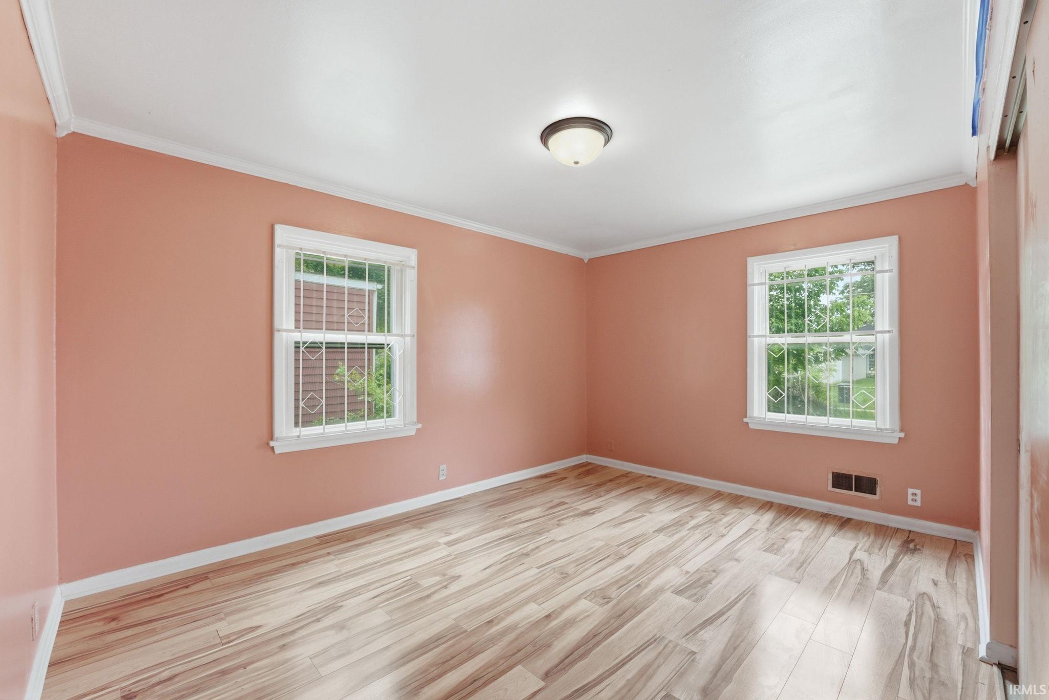 Bright room featuring wood-finish flooring, two large windows, white trim, and a ceiling-mounted light fixture