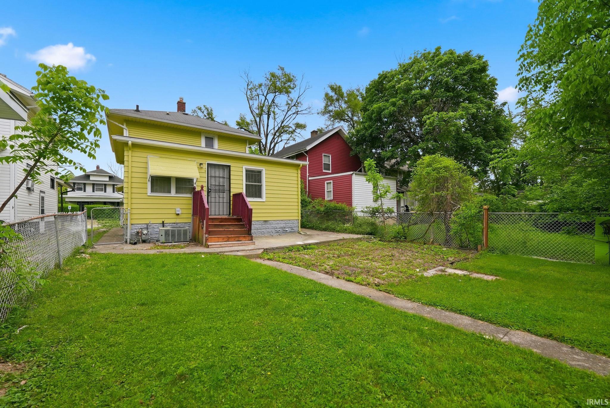 Expansive green lawn with a concrete pathway leading to the rear entrance