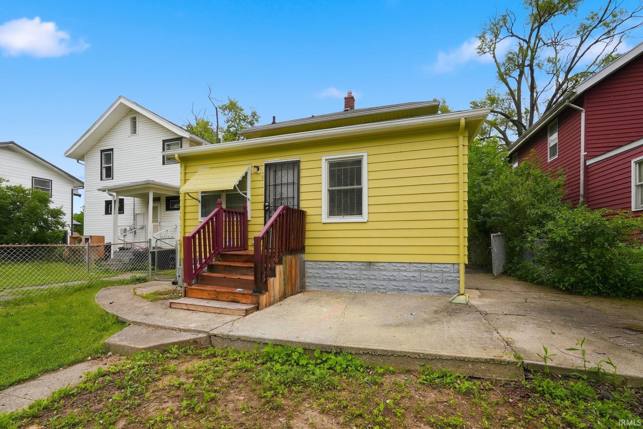 Yellow siding exterior with a concrete patio