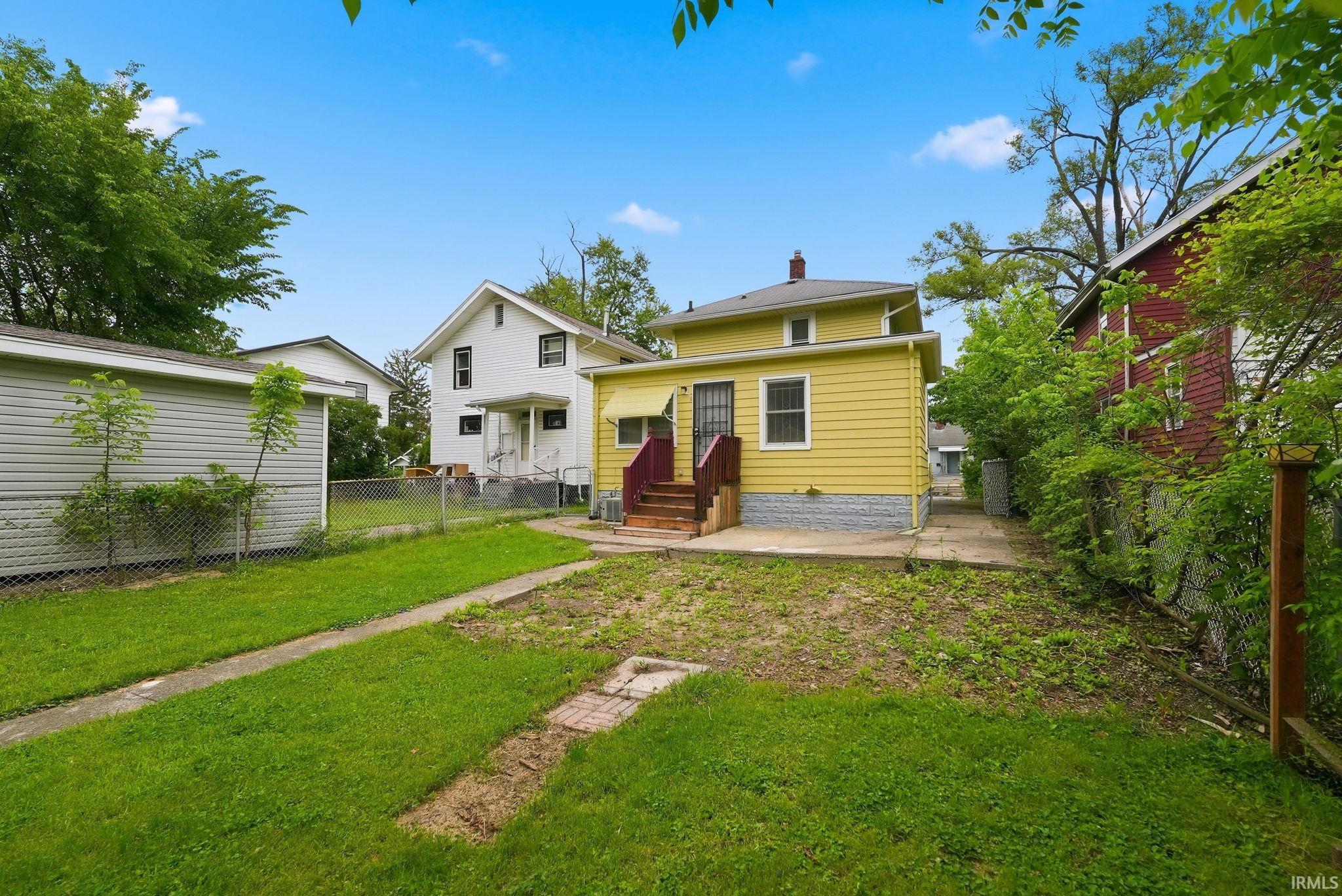 Rear exterior featuring yellow siding and red-painted wooden stairs with railings