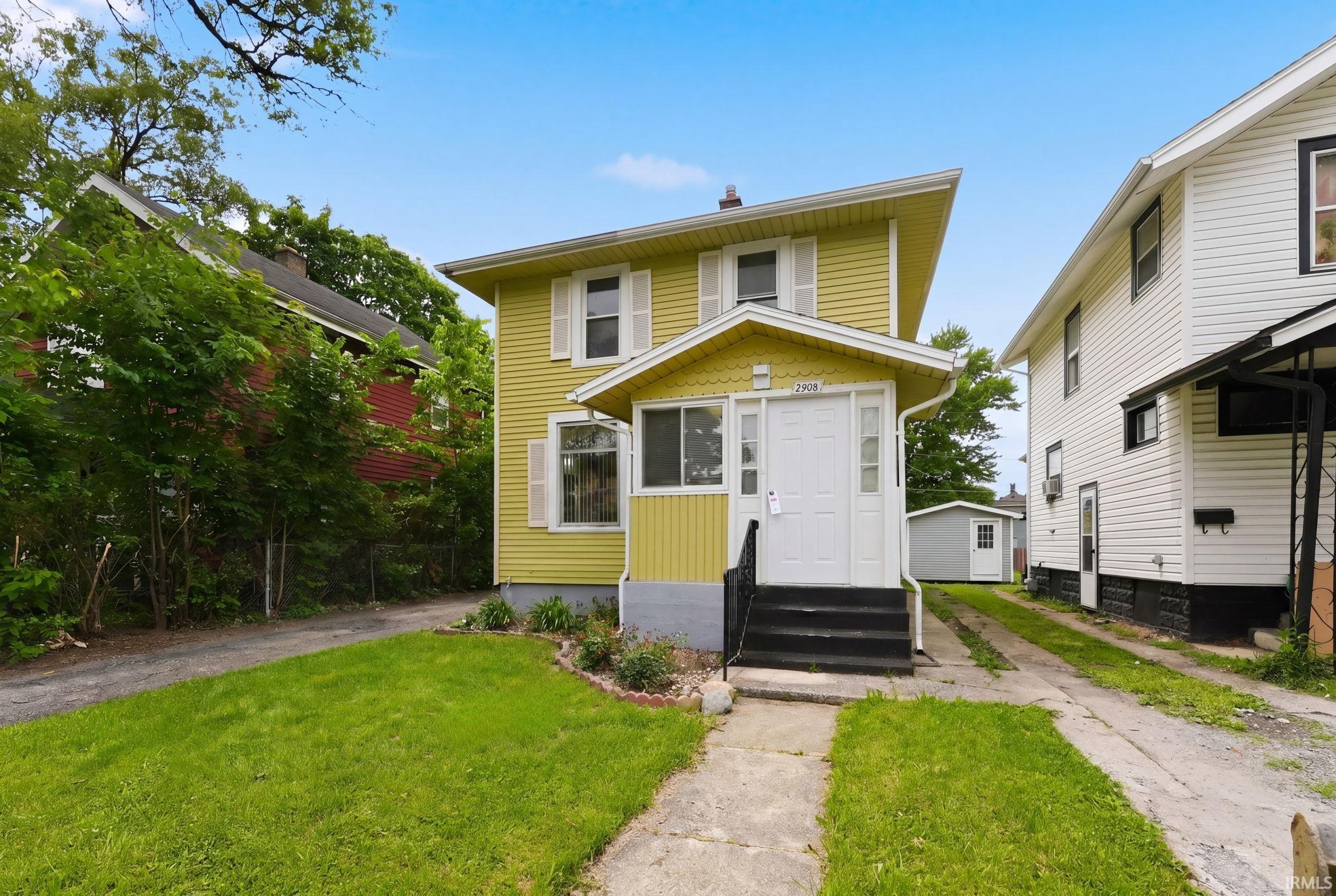 Two-story residence featuring yellow siding, a covered porch entrance, and white window shutters