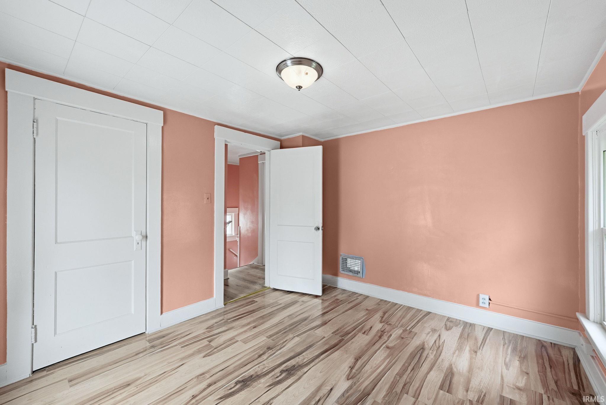 Room featuring wood-finish flooring, white paneled doors, and a ceiling-mounted light fixture