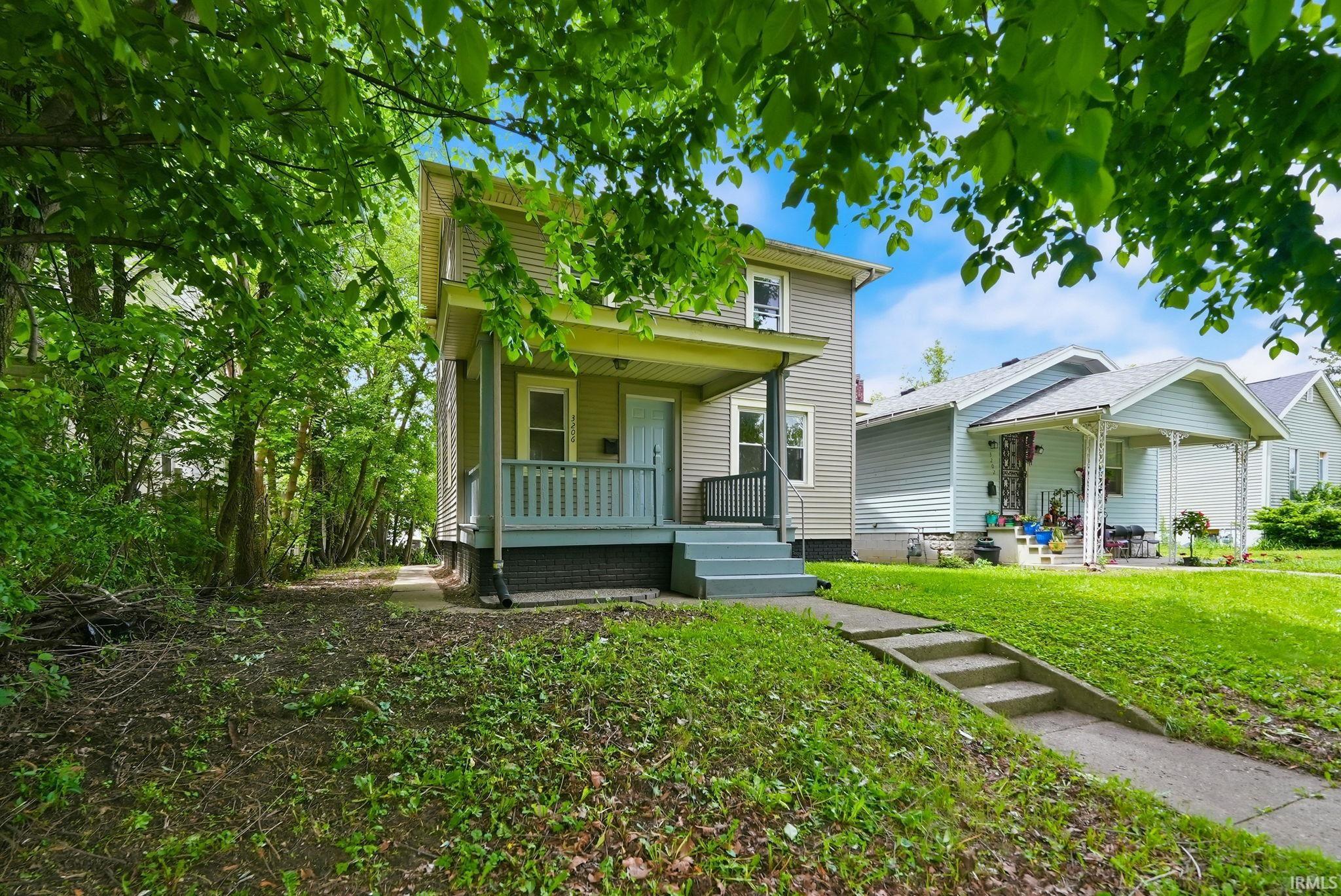 Two-story residence featuring light green siding and a covered front porch with a gray railing