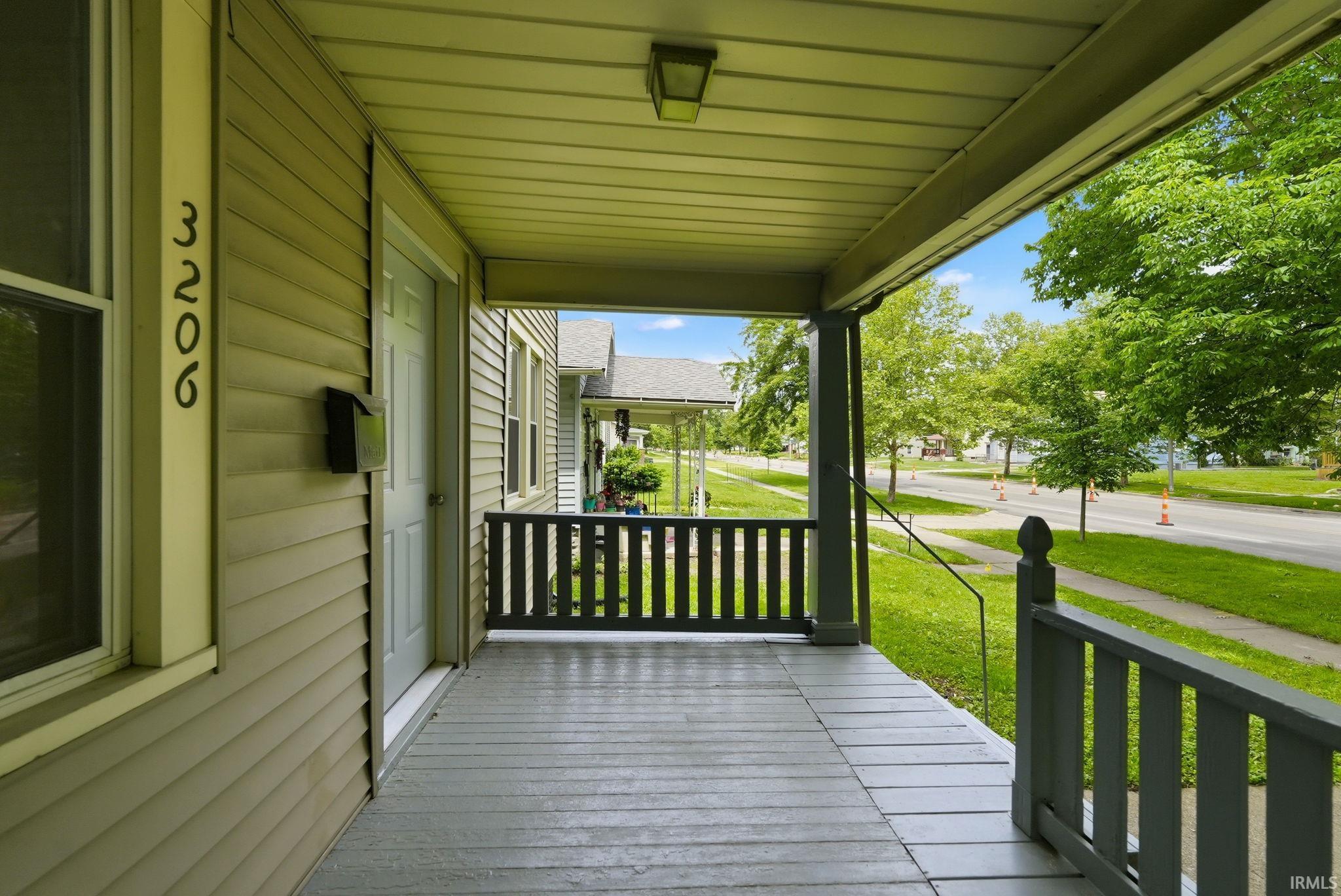 Inviting front porch with painted wood flooring and painted wood railings