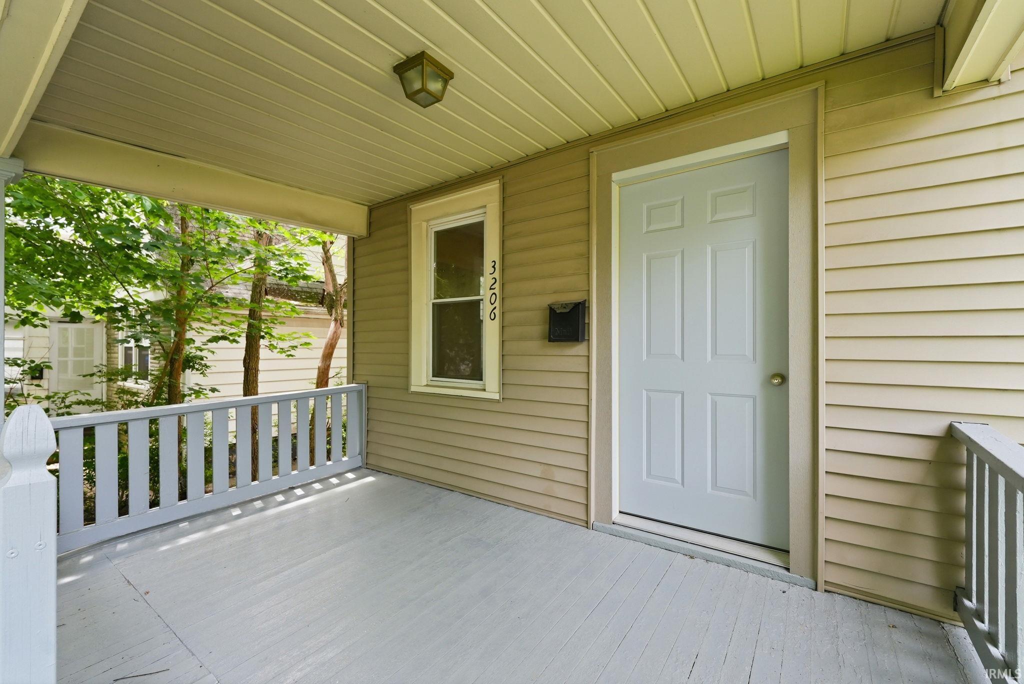 Covered front porch featuring a painted wood floor and white spindle railing