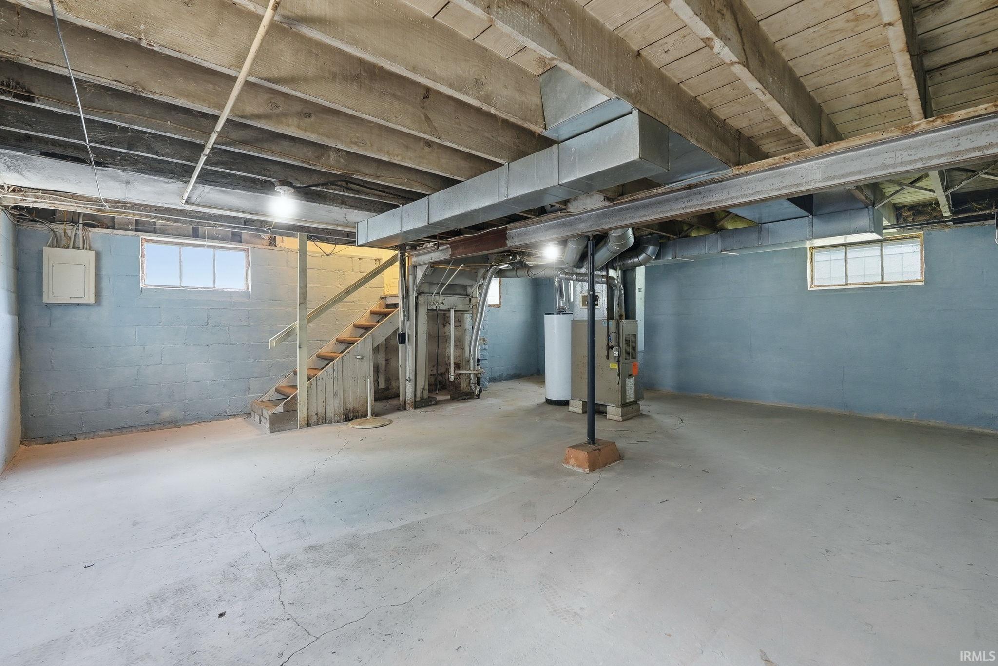 Expansive unfinished basement featuring concrete flooring and painted cinder block walls