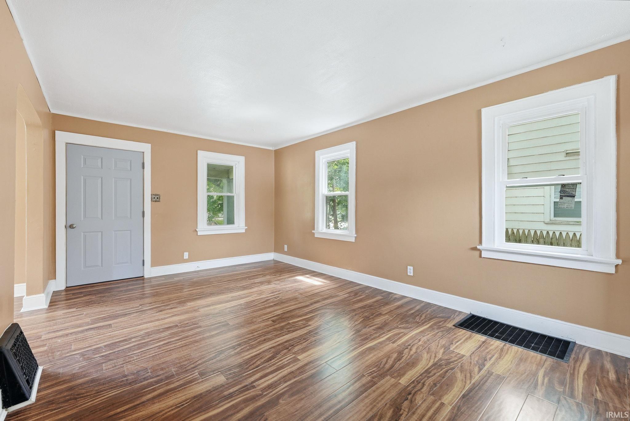 Spacious interior room featuring wood-finish flooring, neutral wall tones, and white trim
