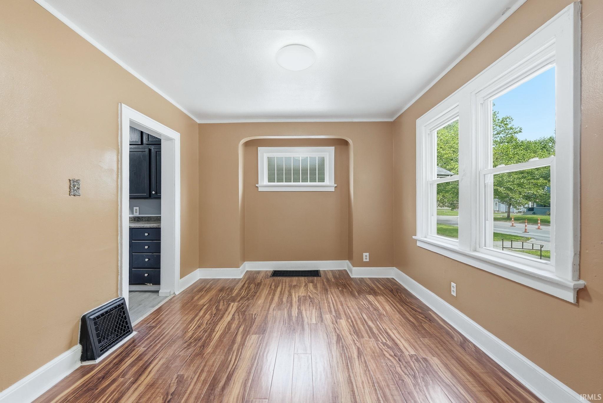 Open-concept living space featuring wood-finish flooring, warm-toned wall paint, and white trim