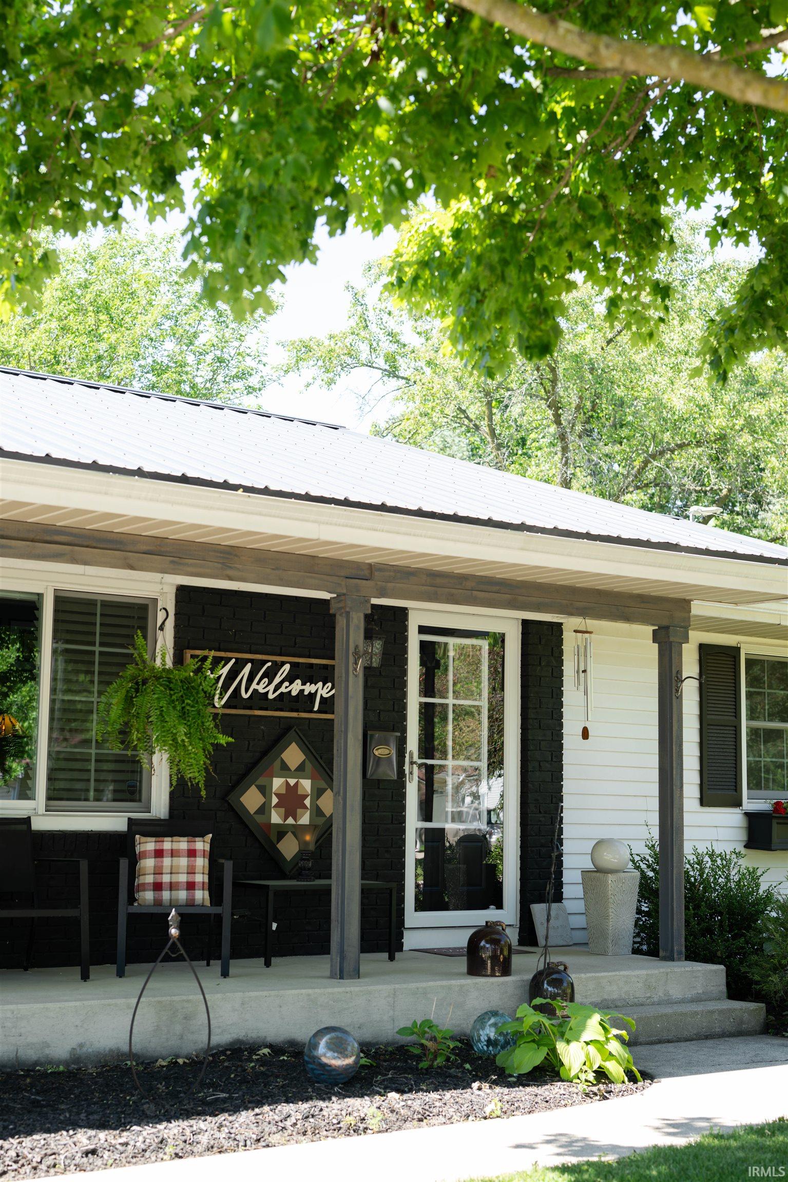 Exterior featuring a white metal roof, dark gray columns, and a white front door with multiple panes