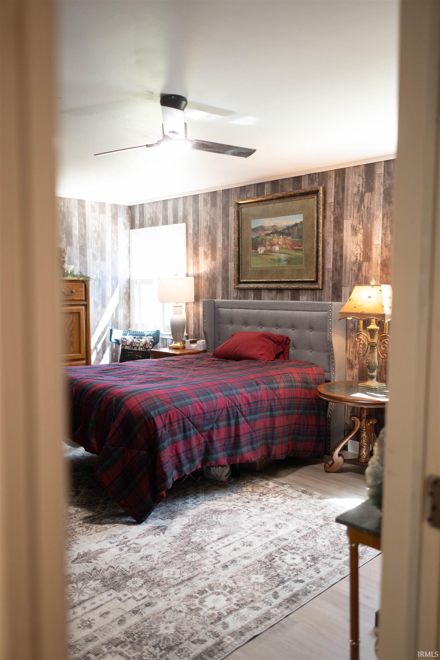 Spacious room featuring light wood-finish flooring, a contemporary ceiling fan, and a wood-paneled accent wall
