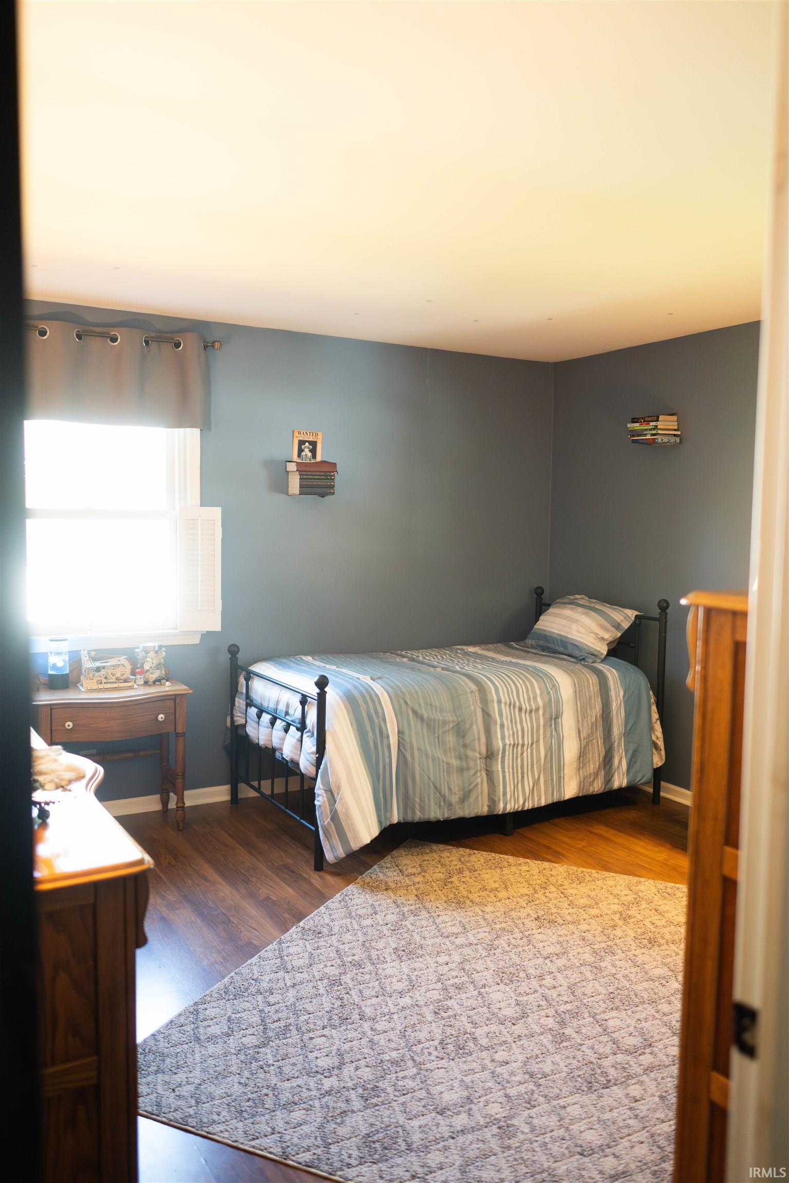 Room featuring wood-finish flooring and a light grey area rug