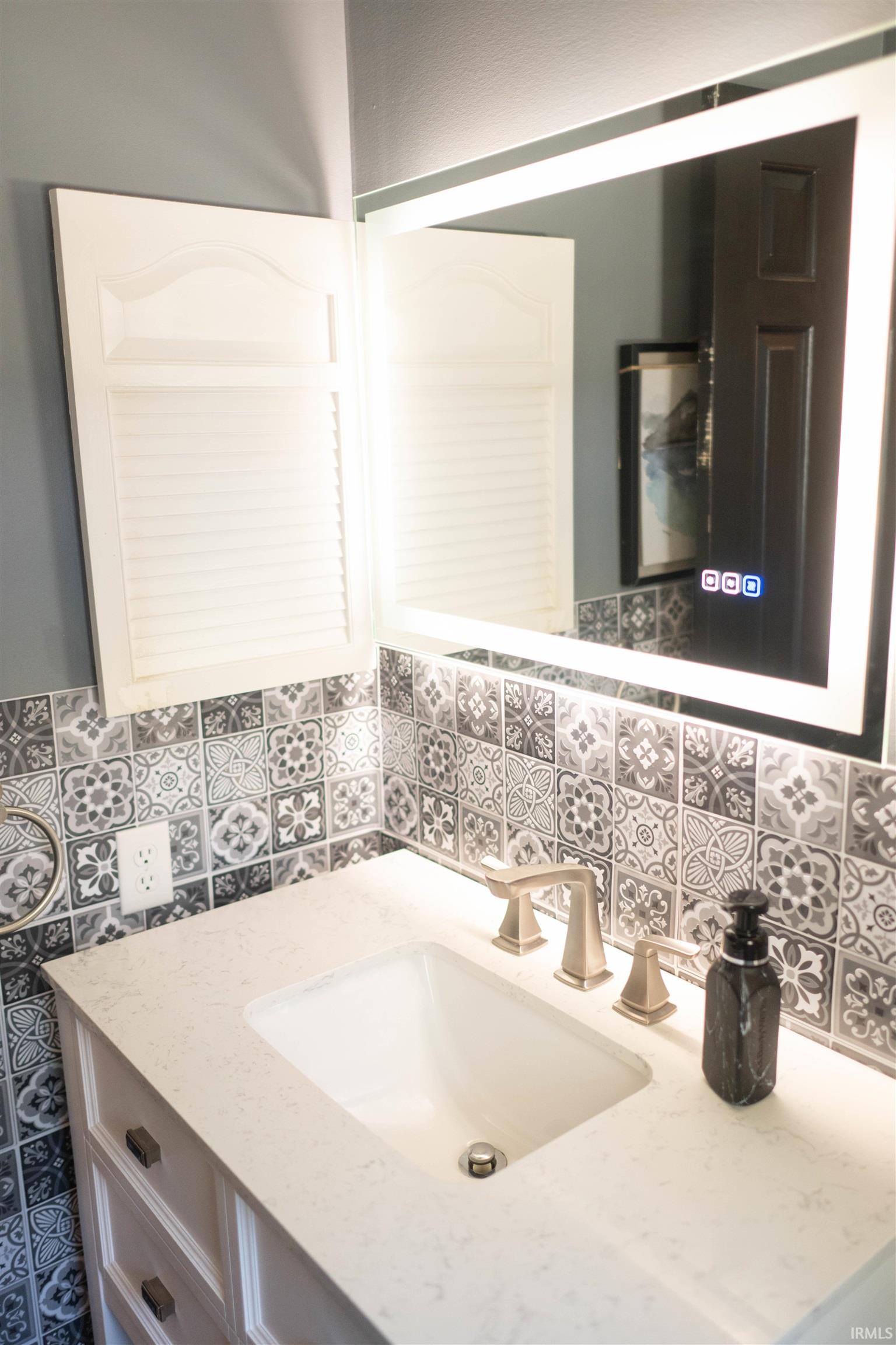 Bathroom vanity featuring a light countertop, undermount sink, and brushed nickel faucet