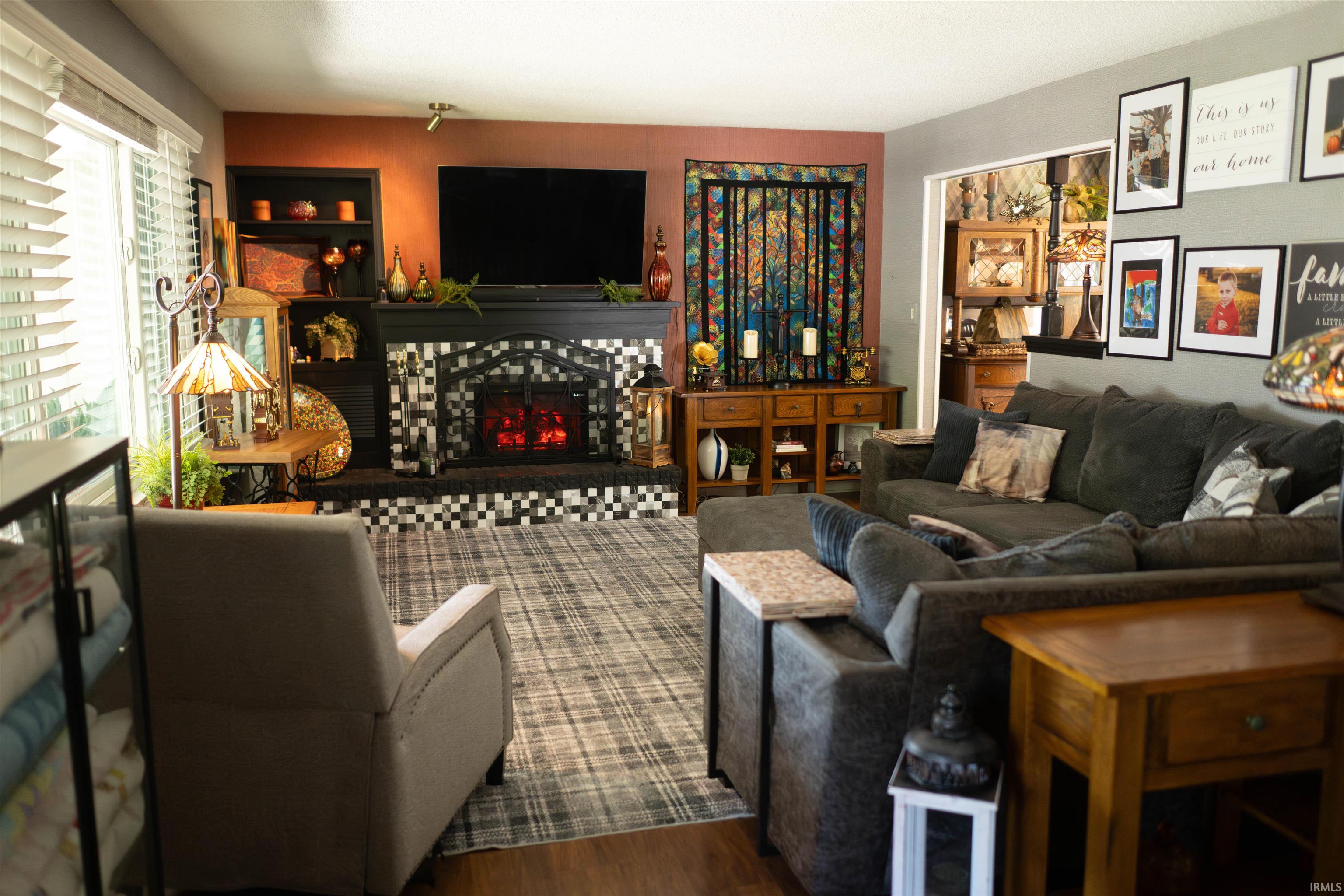 Living area featuring a tiled fireplace with a black mantel, an integrated media niche, and built-in shelving