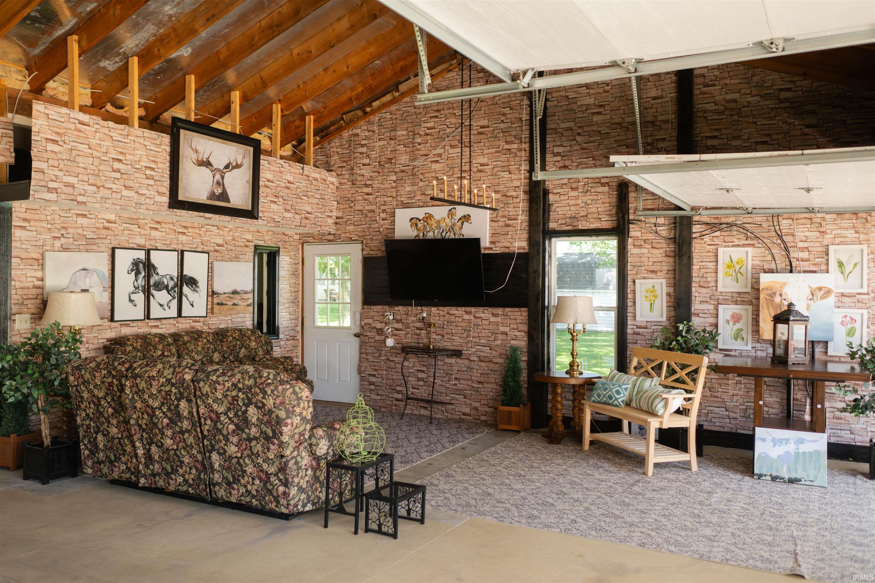 Interior space featuring exposed wood ceiling beams, faux brick wall treatment, and a white paneled door with glass inserts