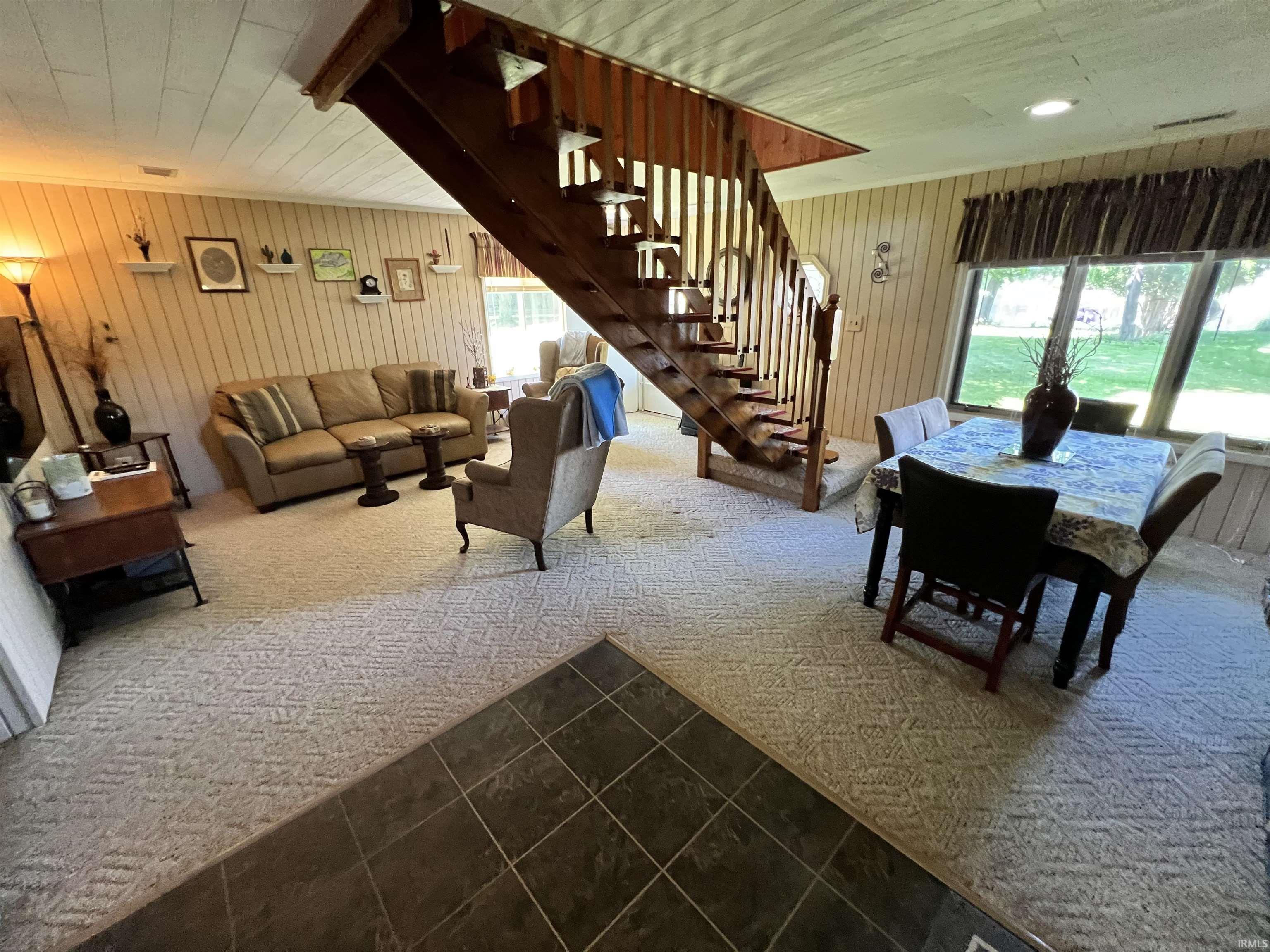 Open concept room featuring a wood-finish staircase, paneled walls, and recessed lighting
